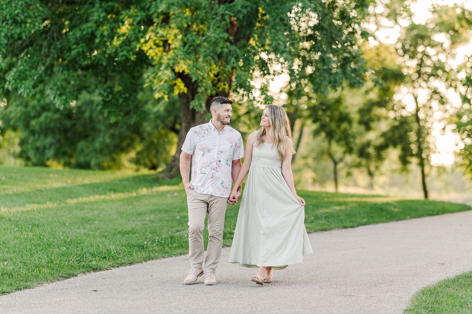 A couple takes a romantic stroll together on a tree-lined path at sunset.
