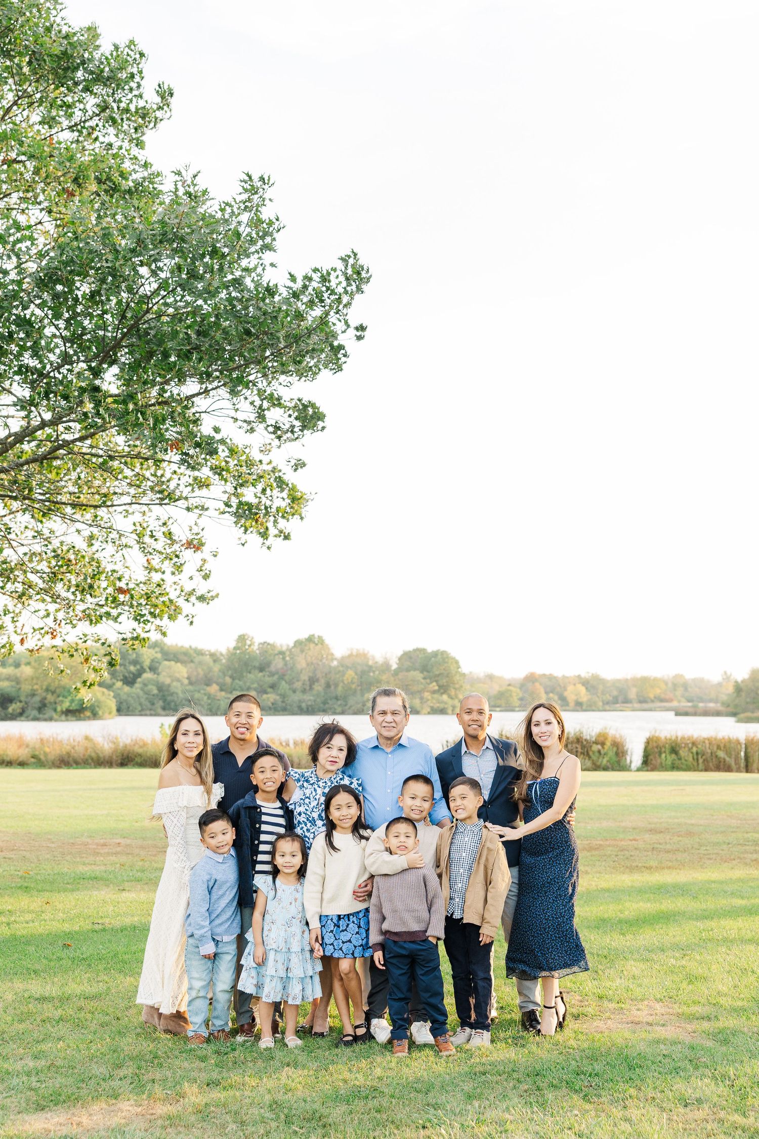 A group of people gather together for a casual outdoor photo session in a grassy field during golden hour. Busse Woods