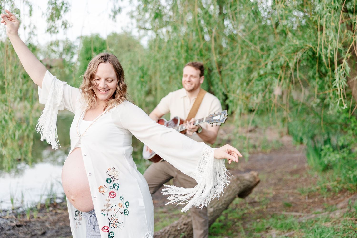 Mother dancing while father plays guitar during a music-inspired maternity session at Veterans Acres in Crystal Lake.