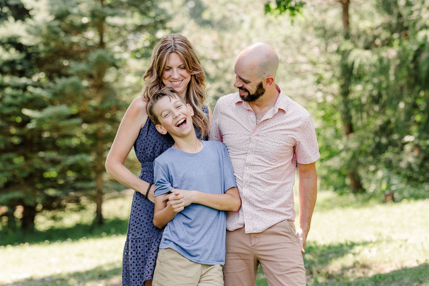 Family of three laughing together during a summer family portrait session in Crystal Lake, Illinois.