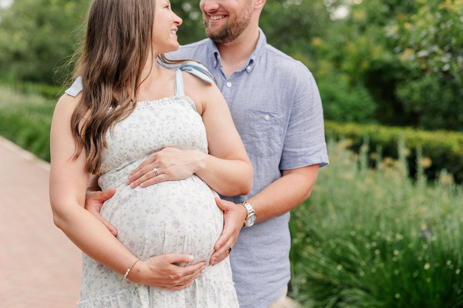 Close-up maternity portrait of expecting parents holding hands over a baby bump