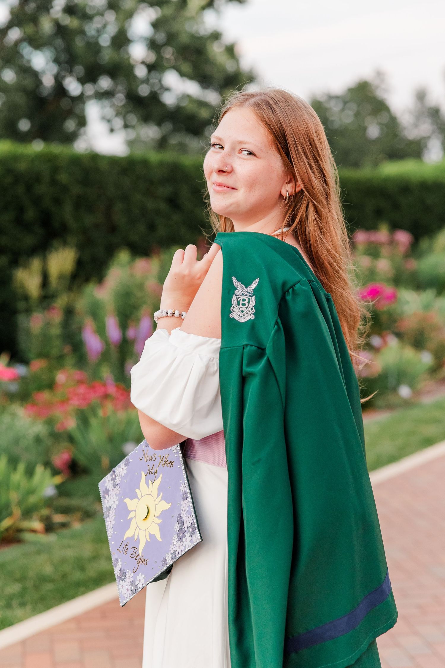 Samantha wears her green graduation gown and holds her decorated cap during her Bartlett High School senior portraits.