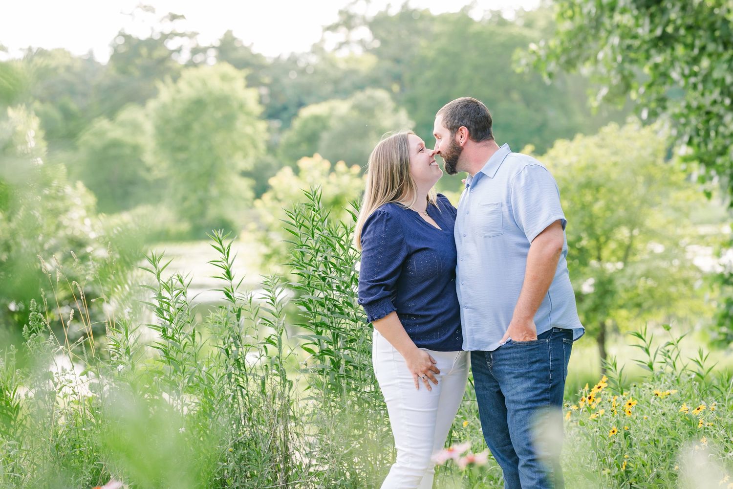 Parents walking through summer greenery during a family photo session at Veterans Acres Nature Center in Crystal Lake