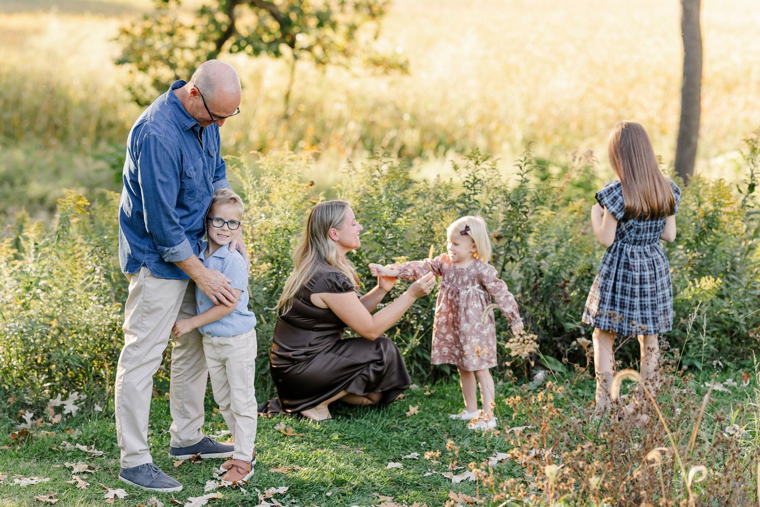 Parents playing with their three children in warm afternoon light during family photos in St. Charles, IL.