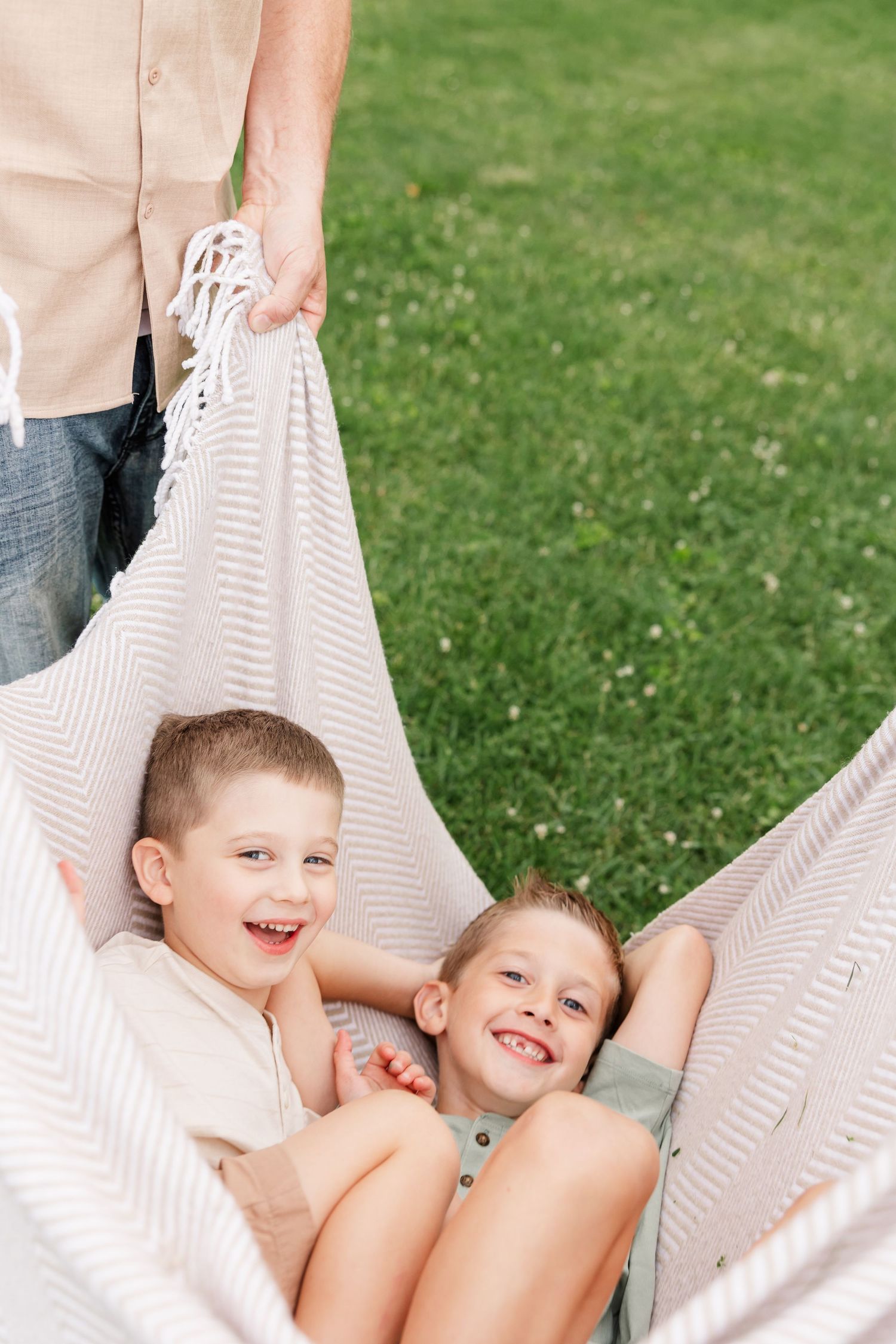 Two young brothers laughing in a blanket swing during a candid family photo session in Crystal Lake, Illinois.