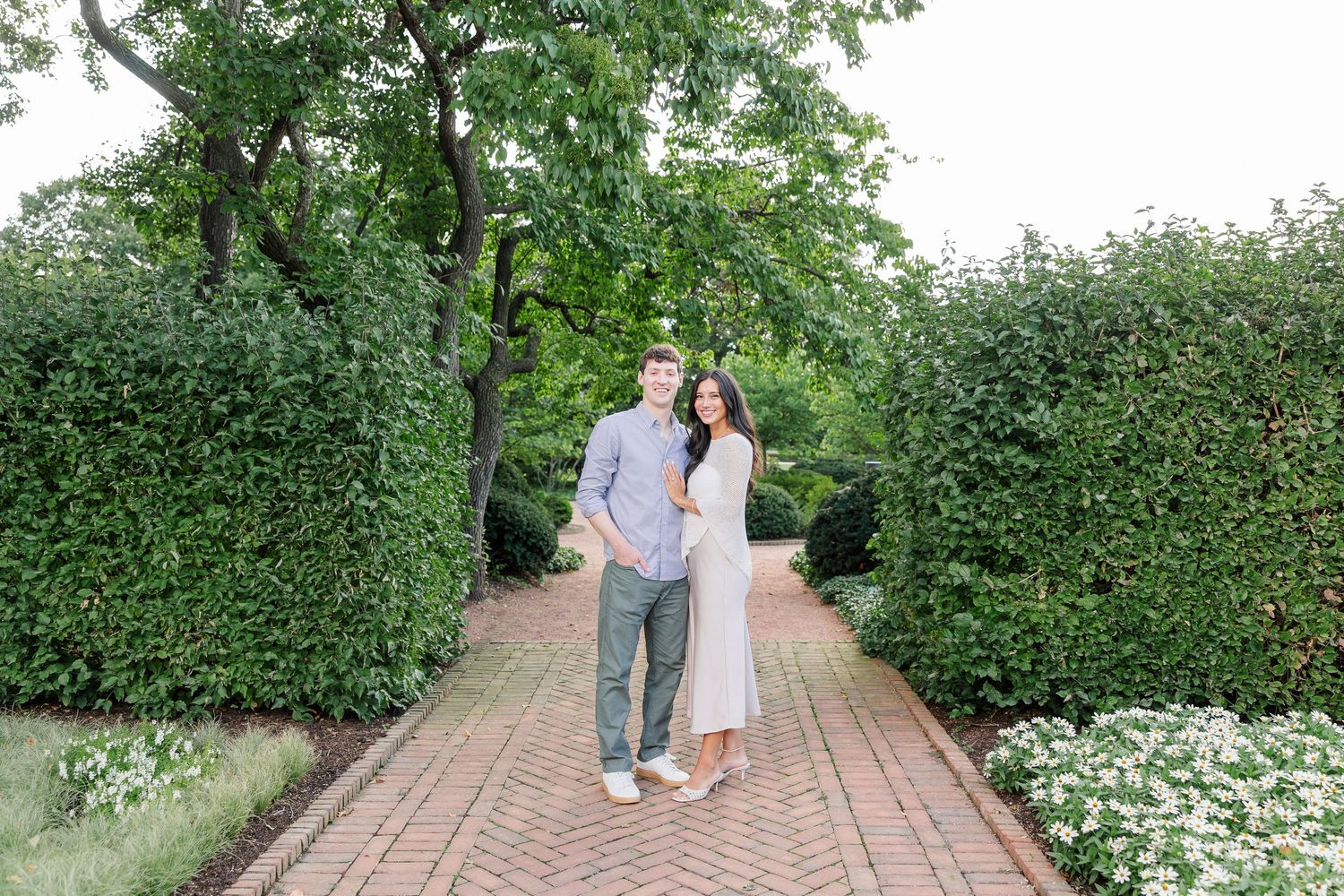 Newly engaged Alysia and Jack smile together along the Octagon Garden pathway.