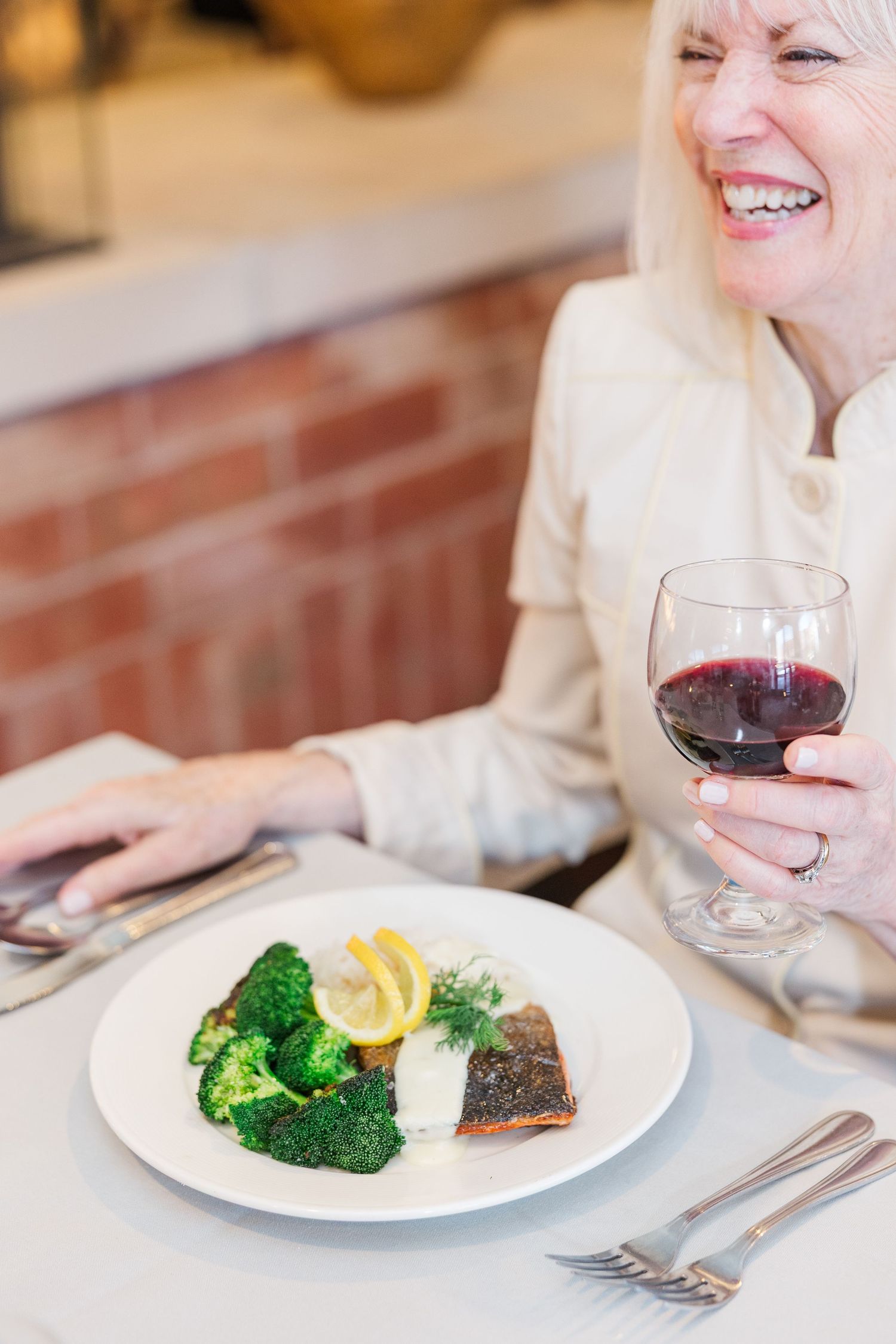 Beacon Hill senior living branding photo in Lombard, Illinois featuring resident enjoying dinner and wine