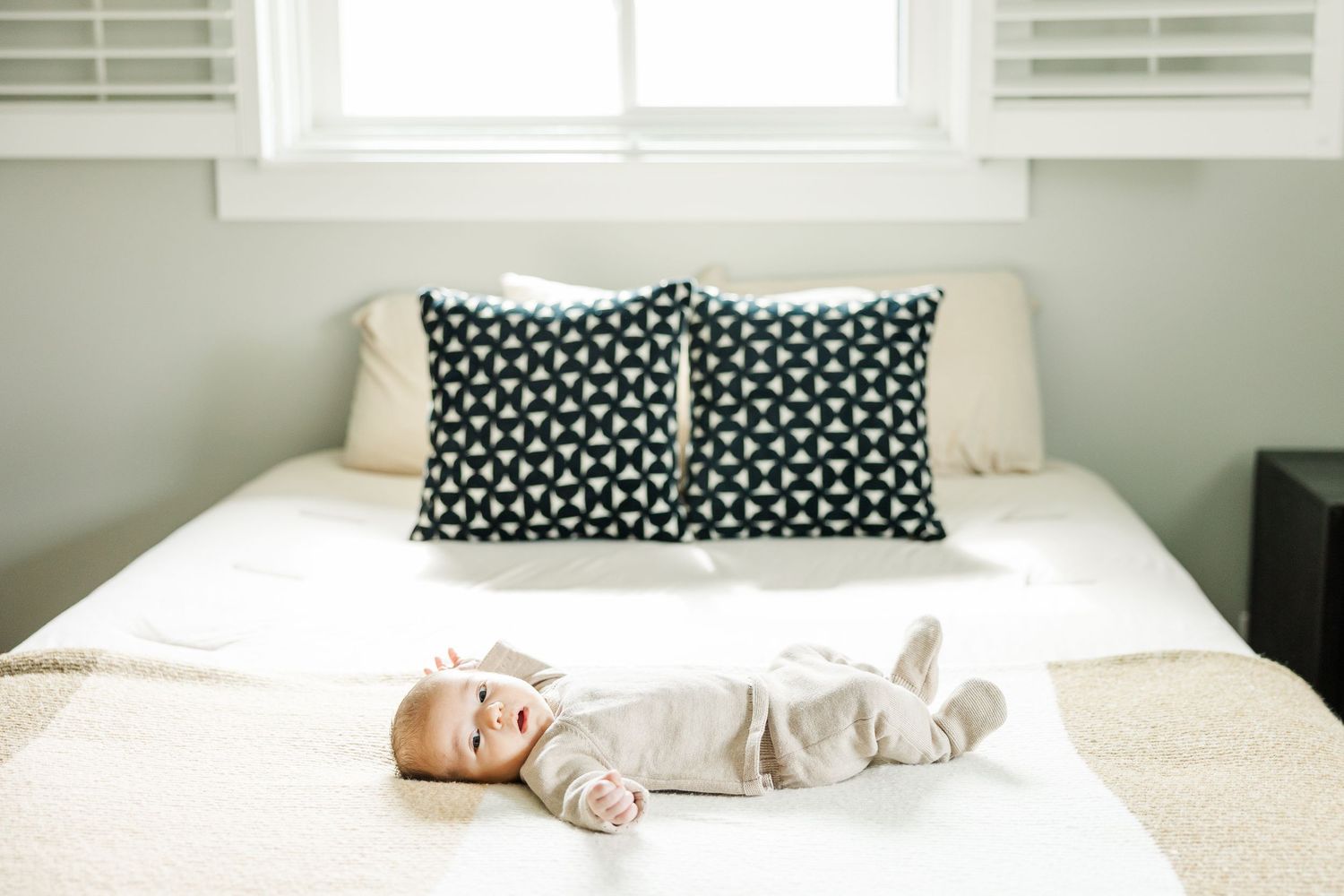 Newborn baby lying on a bed in a bright bedroom during an in-home lifestyle newborn photography session in Palatine Illinois