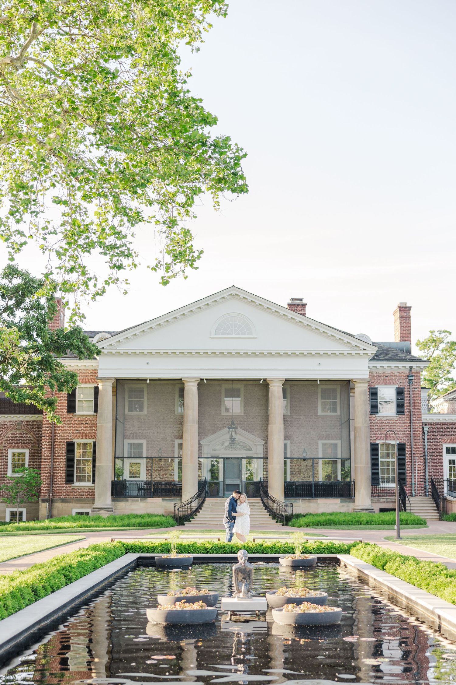 Colonial architecture building with white pillars and a reflecting pool leading to the entrance.