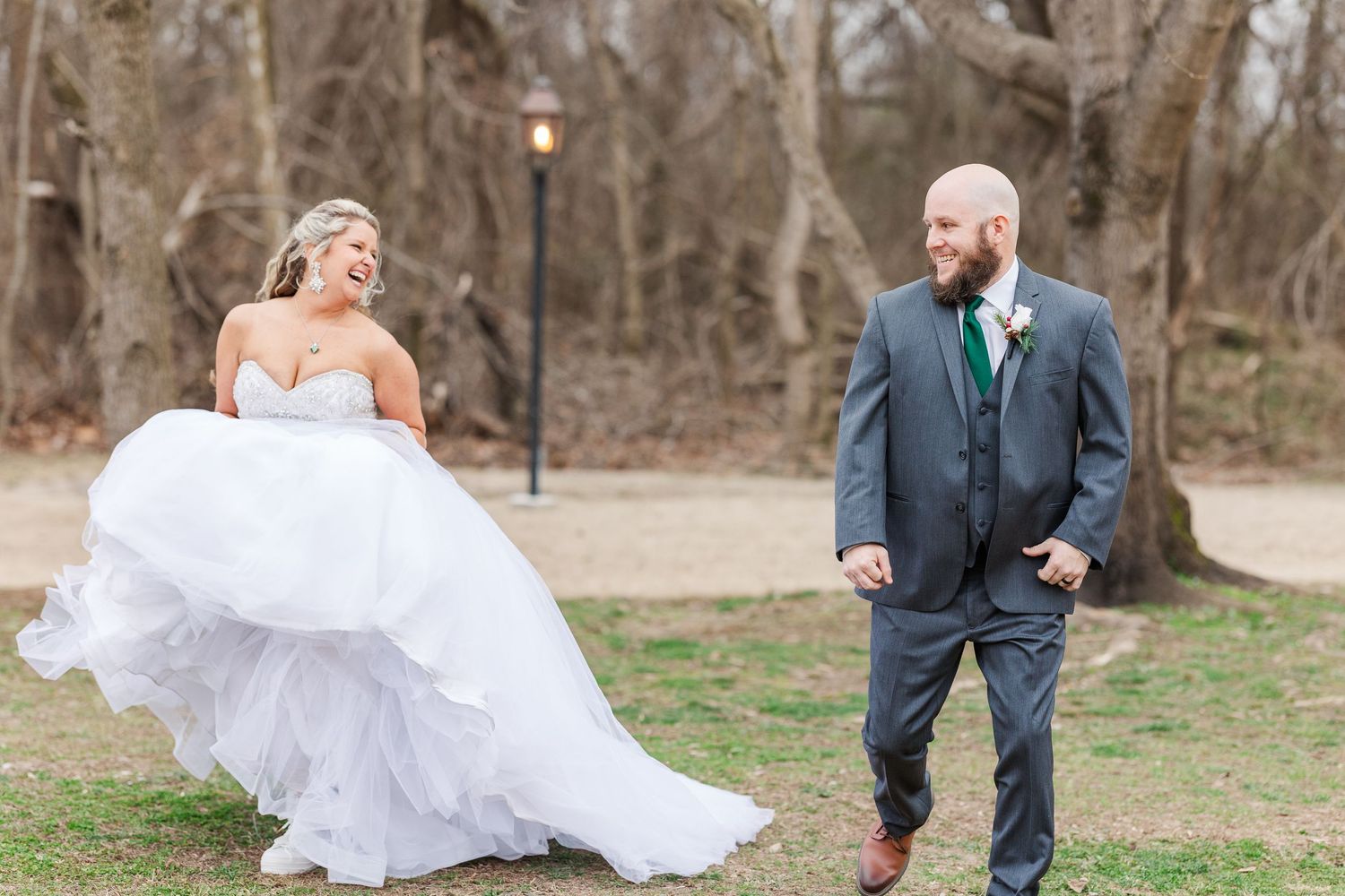 Playful wedding photo showing bride's dress flowing in the wind as couple shares a laugh.