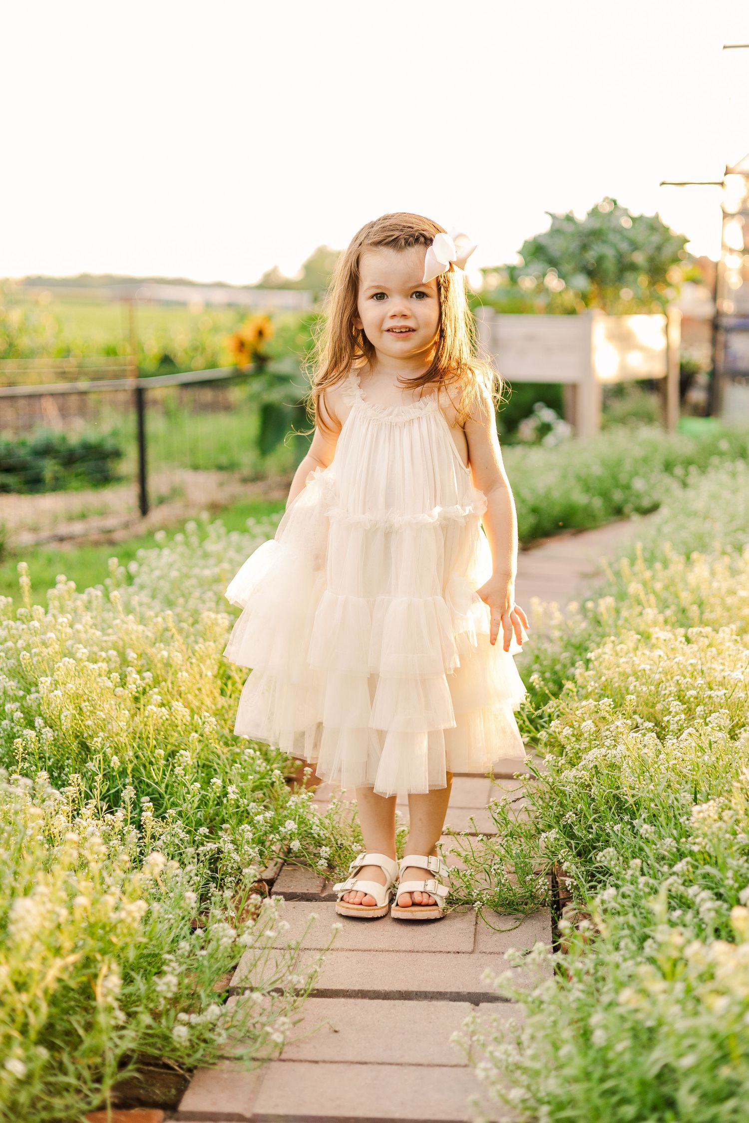 A lovely garden scene with a white ruffled dress against a backdrop of blooming flowers.
