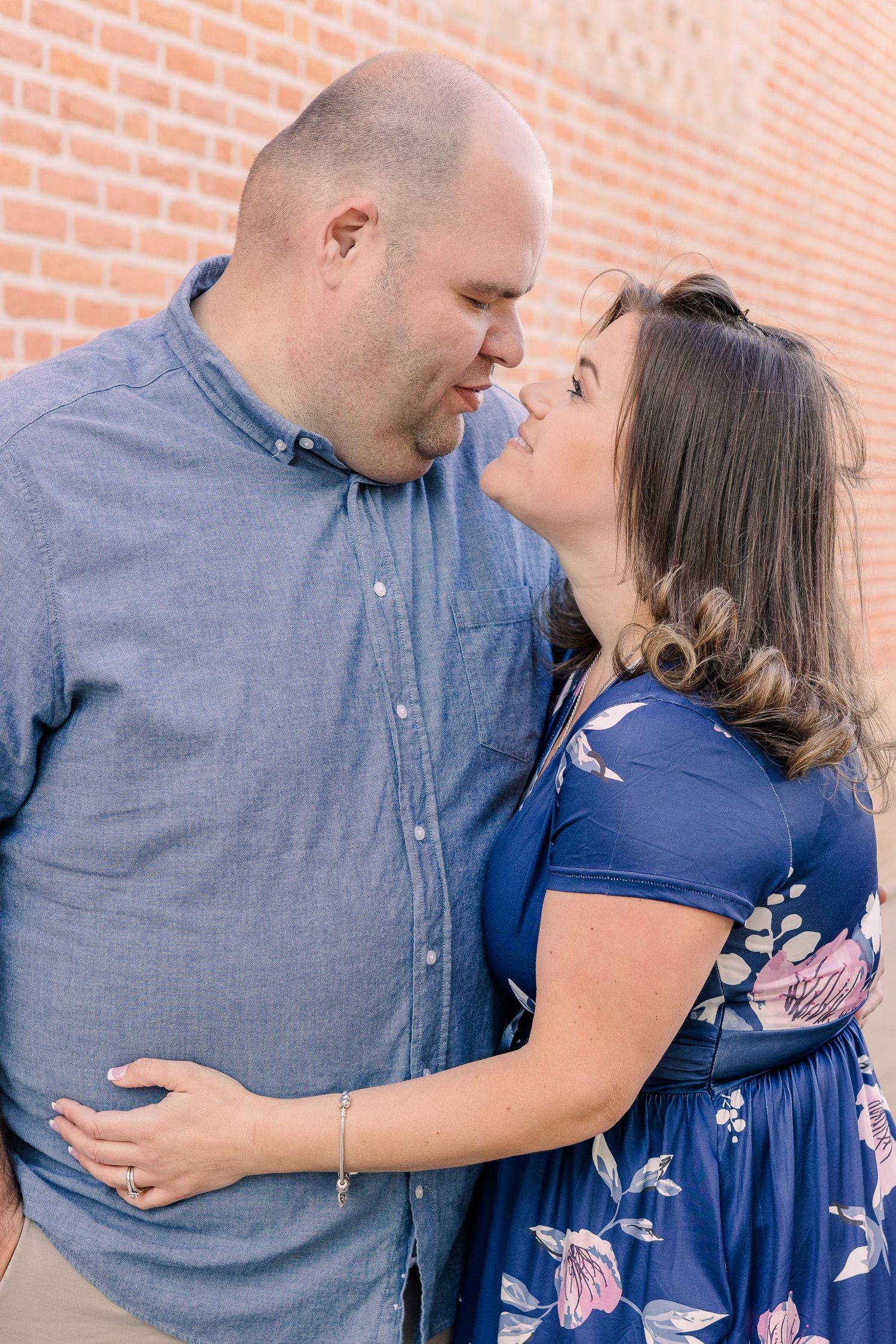 Romantic couple sharing intimate moment against brick wall background.