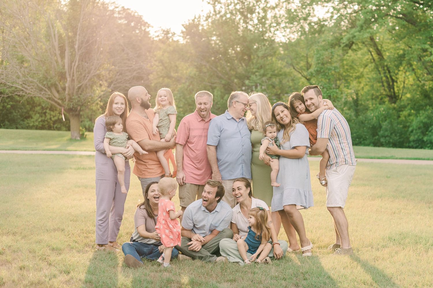Extended family gathering posed together in a sunny park setting.