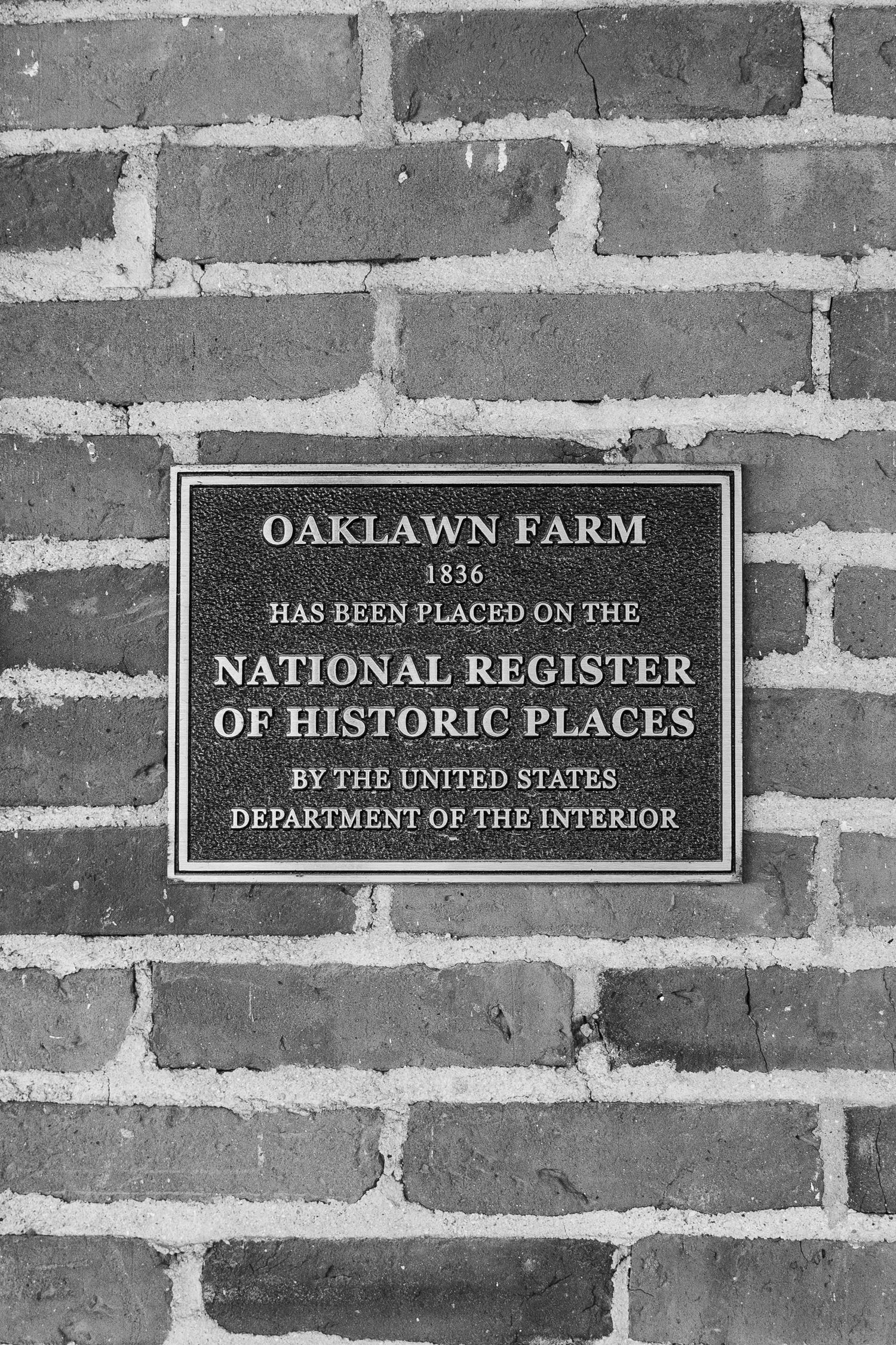 Historic plaque marking Oaklawn Farm's listing on the National Register of Historic Places mounted on brick wall.