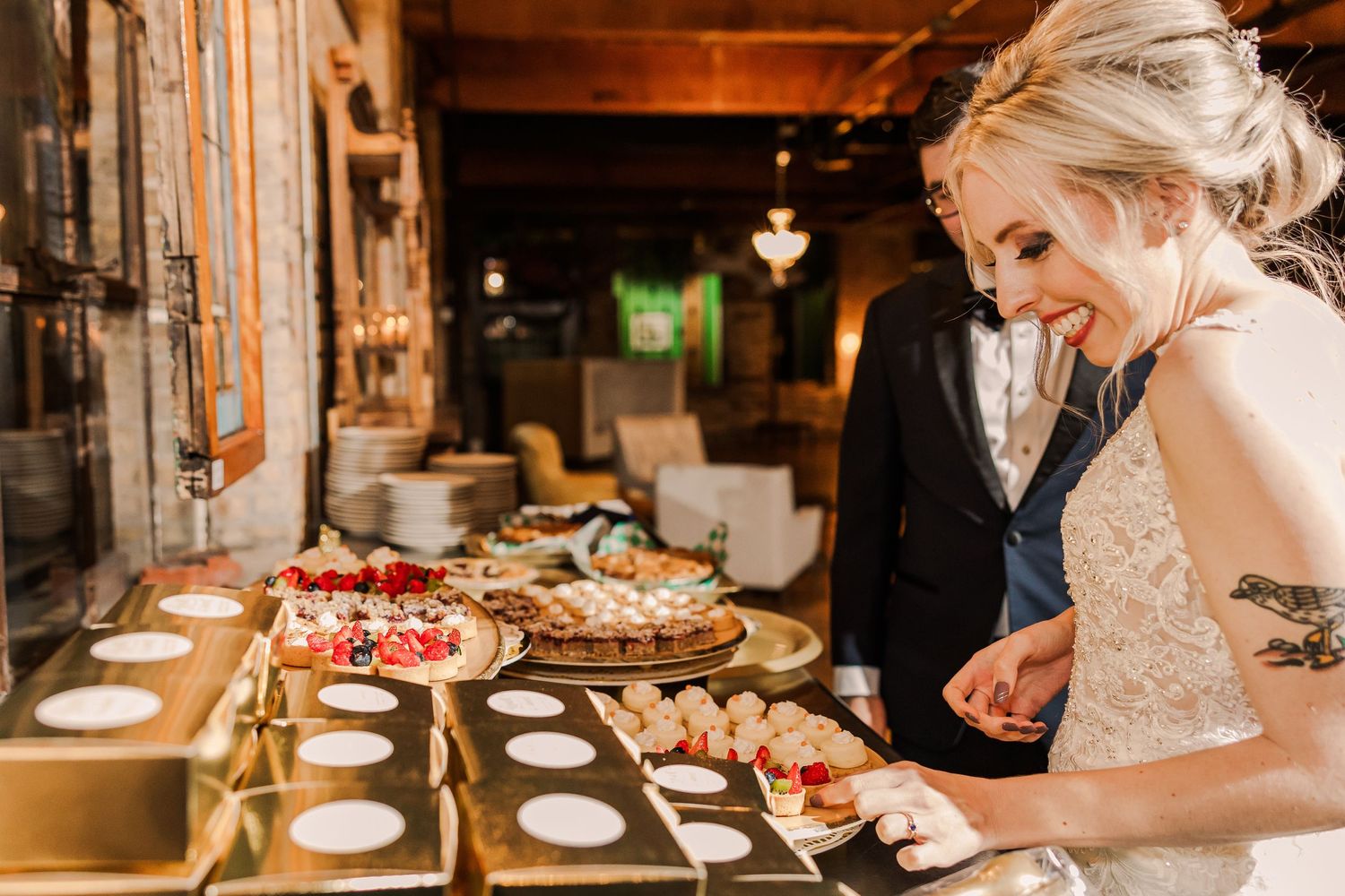 Wedding guests select desserts from elegant display table at reception.