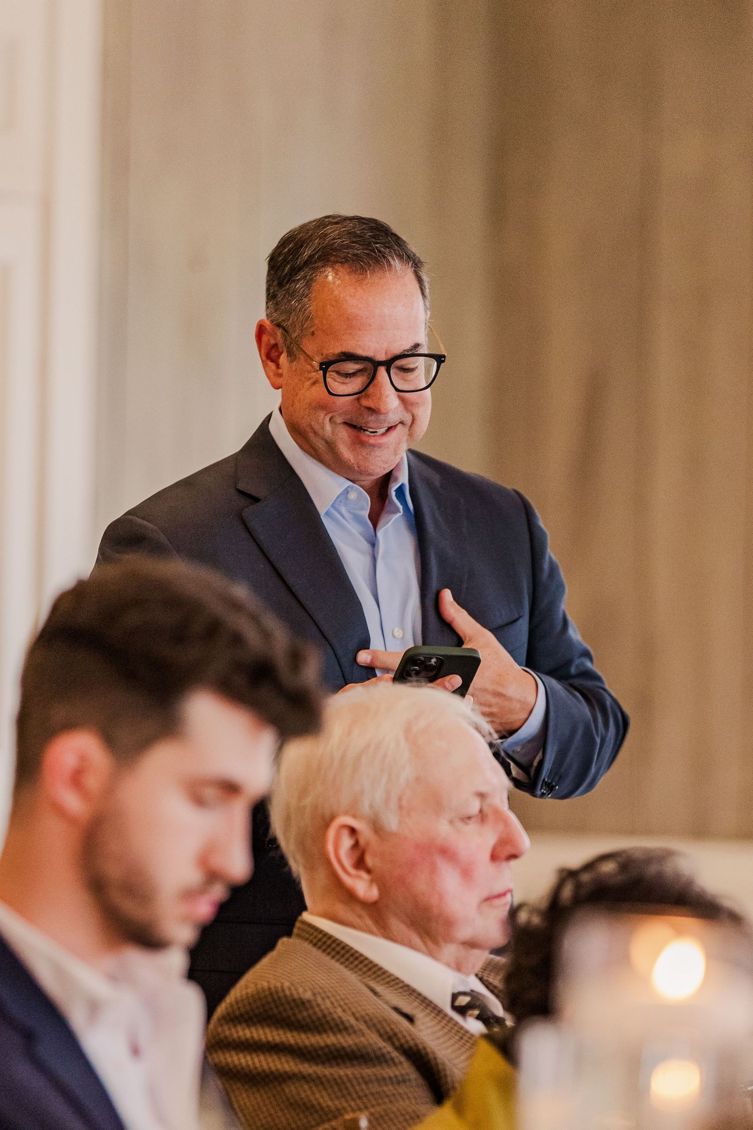 Wedding guest delivering emotional speech at reception dinner while others listen attentively.