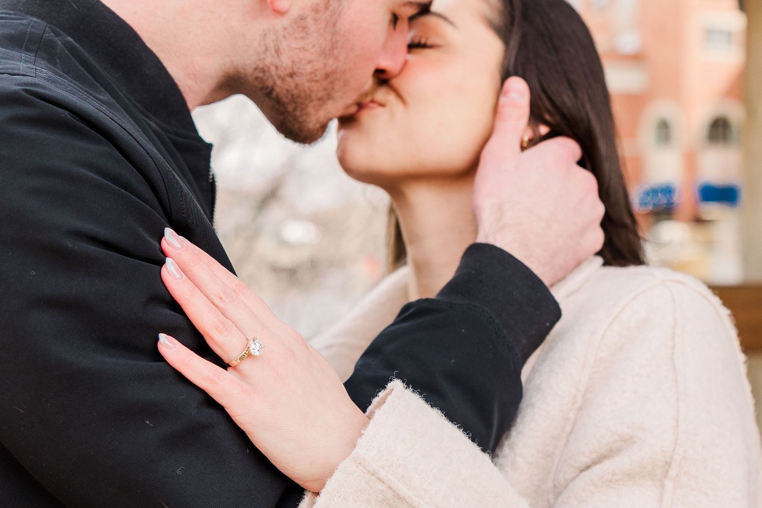 A close-up romantic moment between a couple in contrasting black and cream coats.