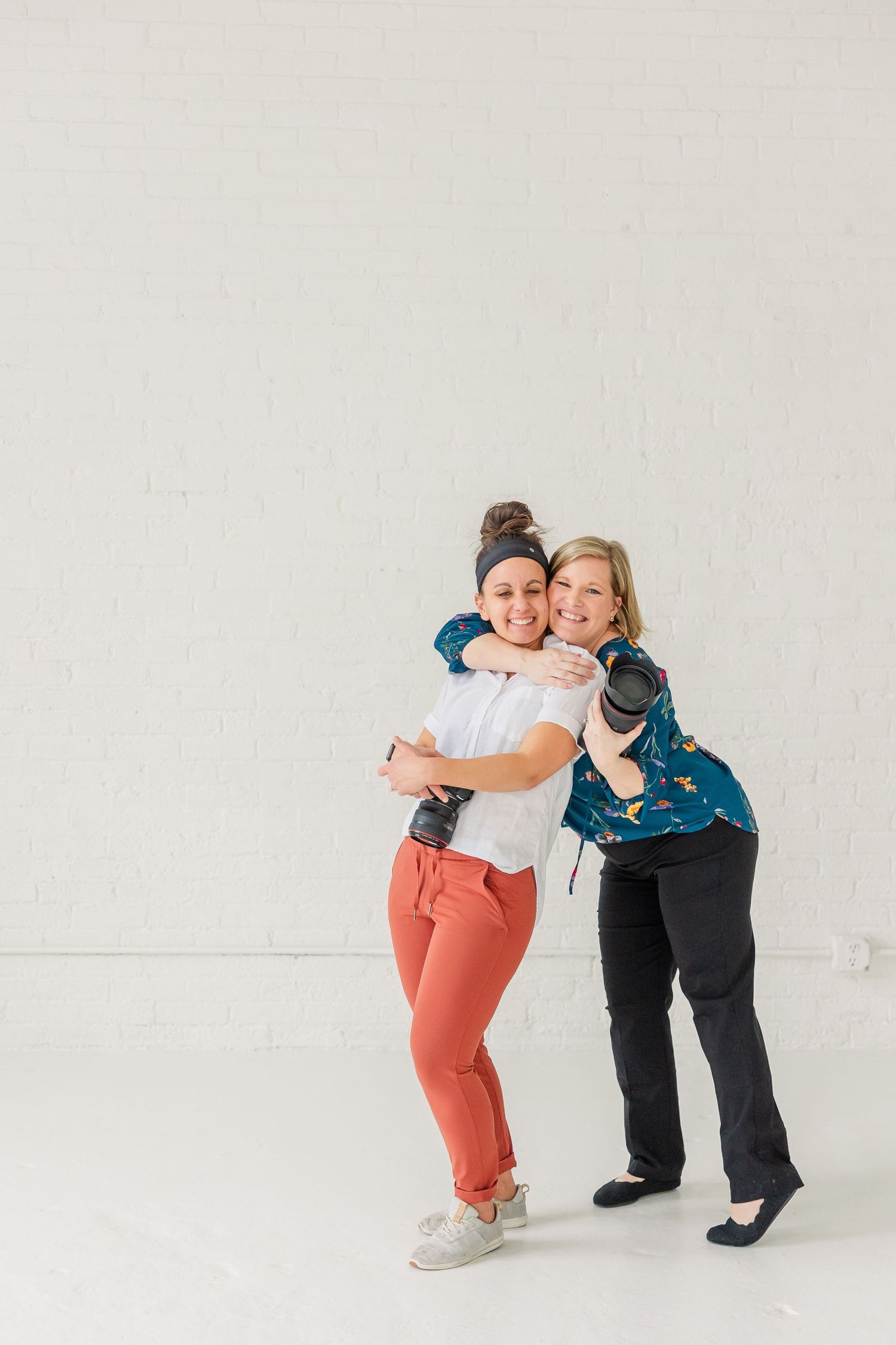 Cassie Lacina and Rachael Watson hugging and posing for a photo at the Studio Chicago with their cameras