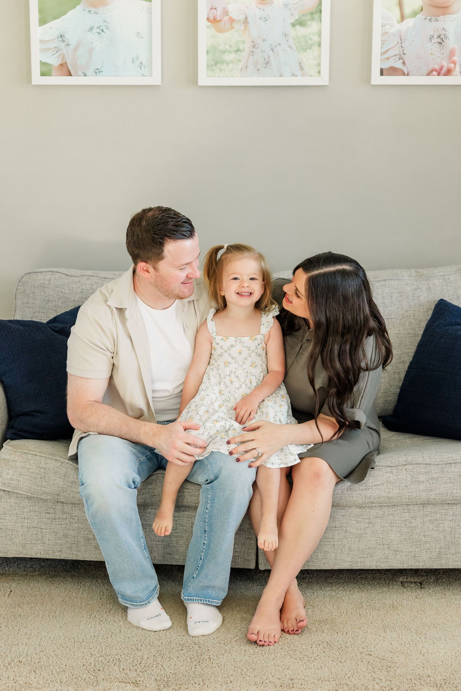 Lifestyle newborn session in Huntley IL with parents smiling at big sister on the couch in their home