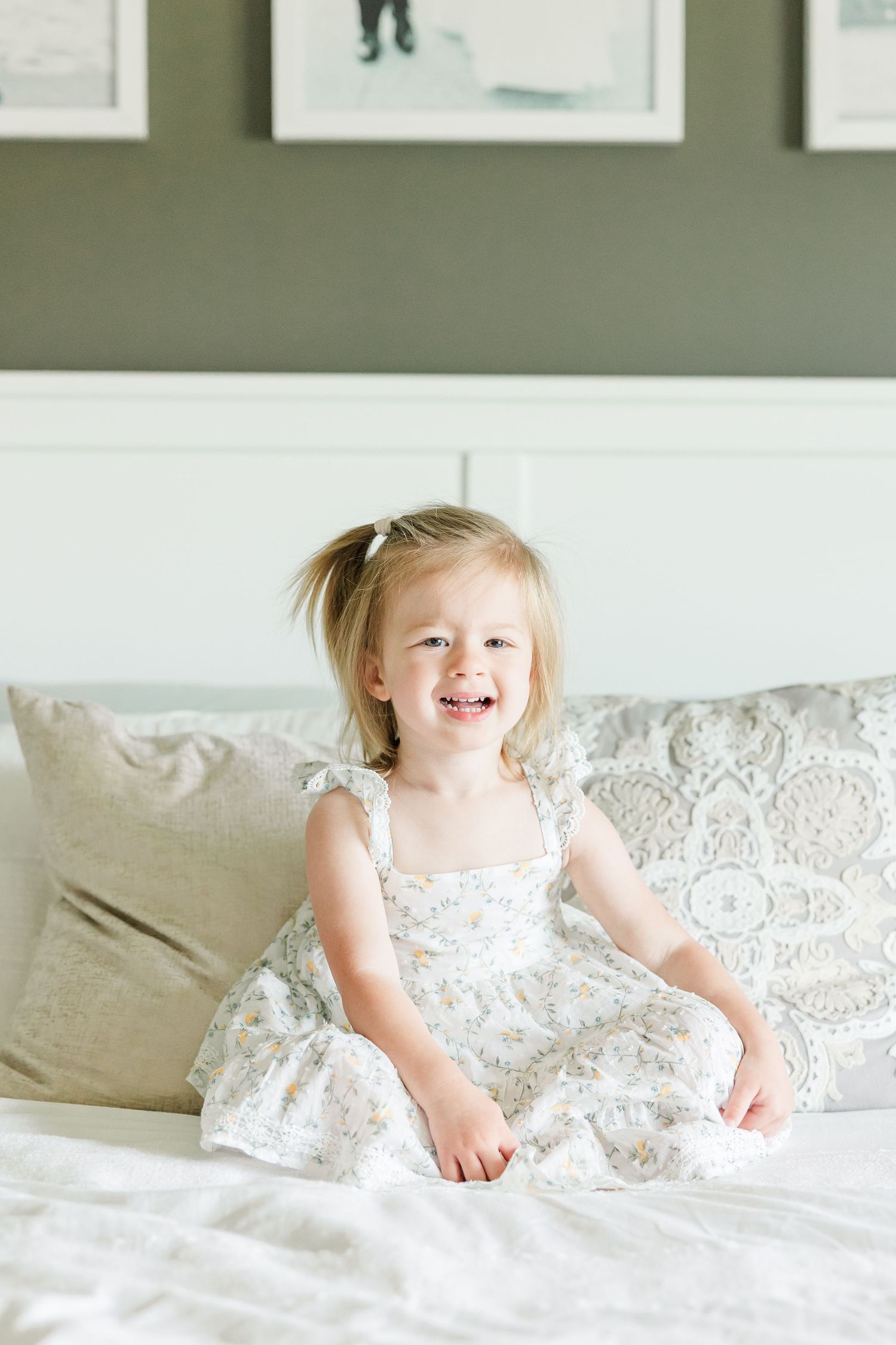 Big sister smiling on the bed during a sweet in-home newborn photography session in Huntley IL