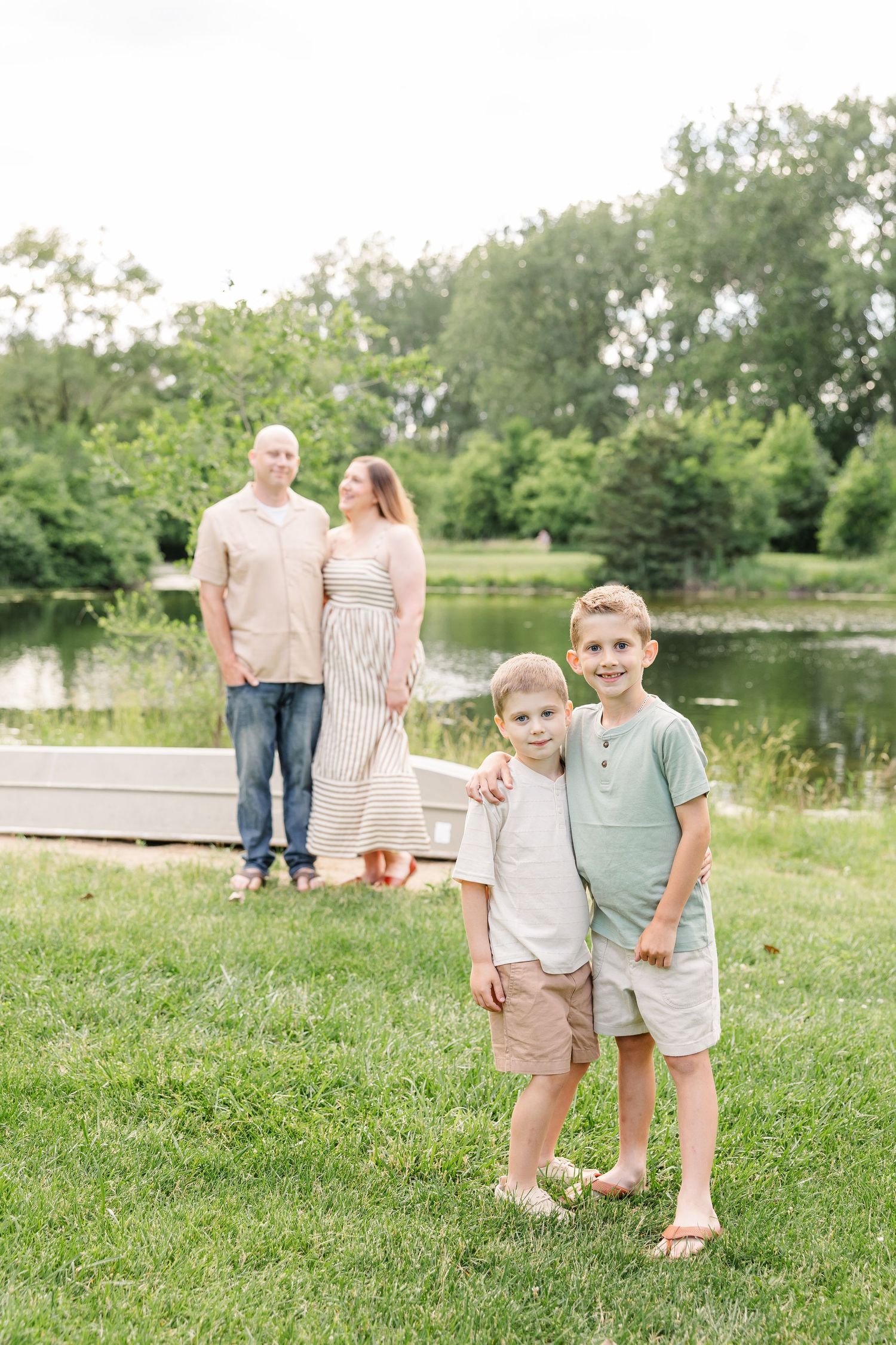 Two young brothers smiling in front of their parents during a Crystal Lake family portrait session at Shamrock Hills Park.