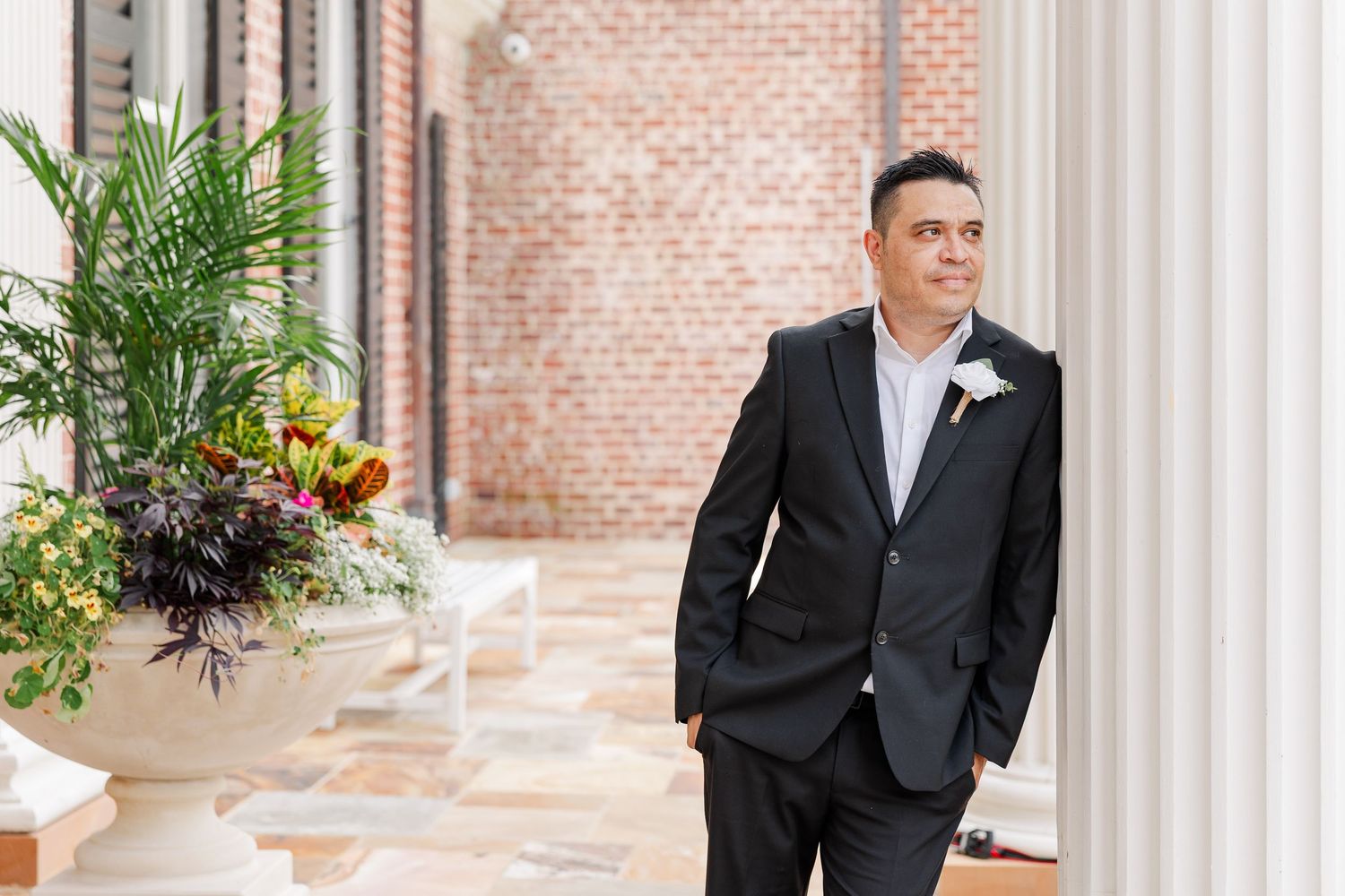 Groom posing beneath the white columns outside McCormick House at Cantigny Park.