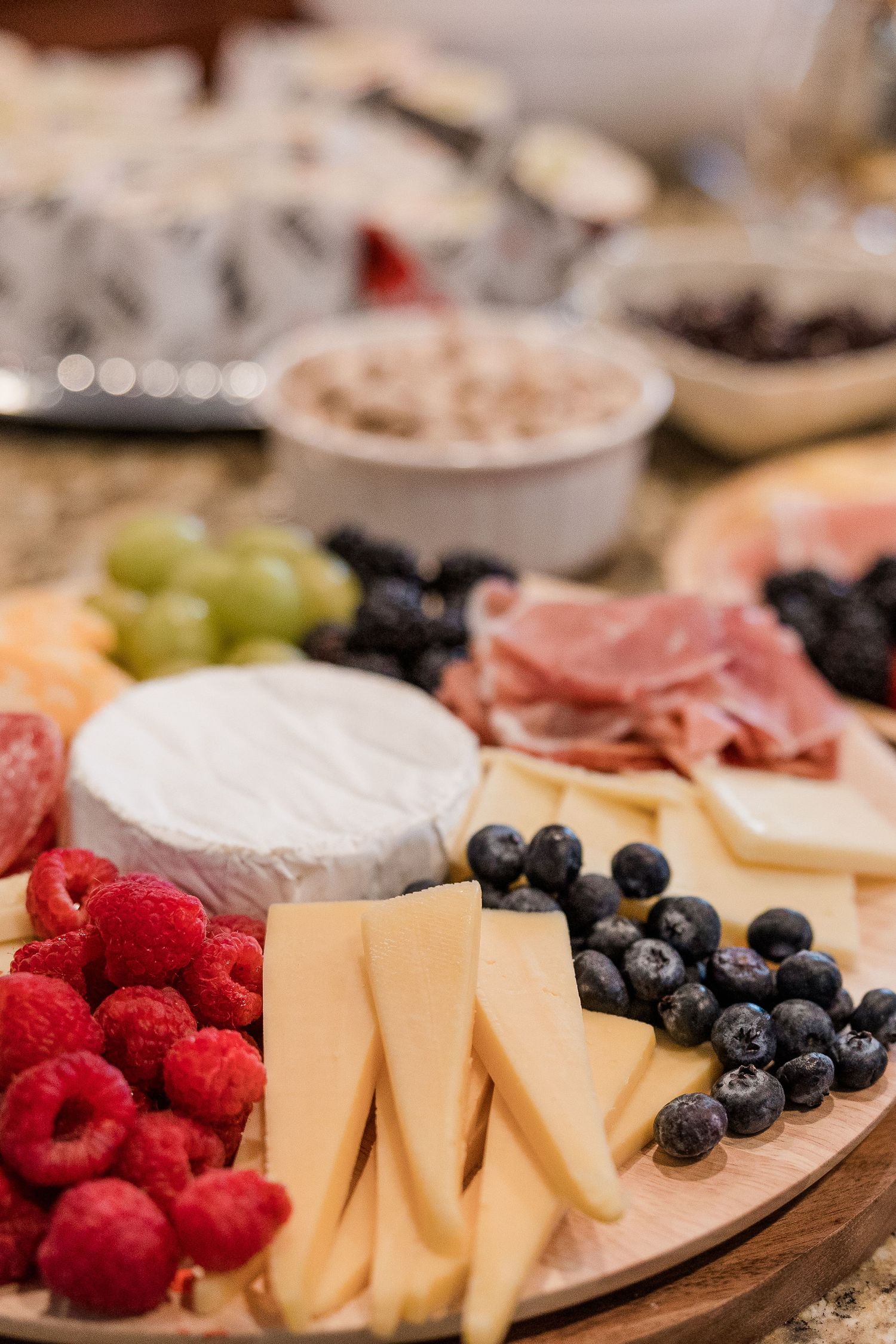Charcuterie board with fresh berries, cheese, meats and grapes arranged beautifully.