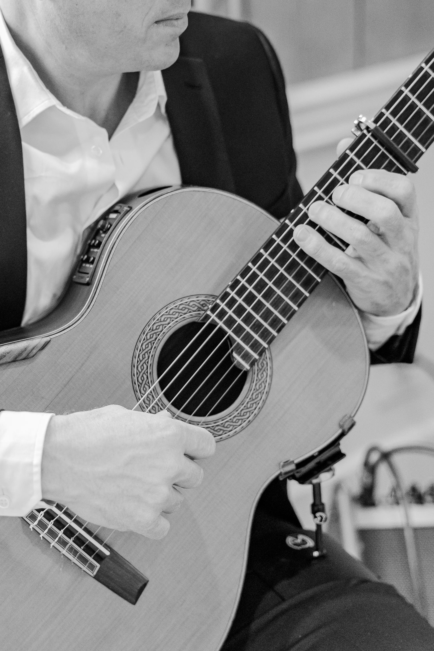 Close-up black and white detail of hands playing classical guitar.