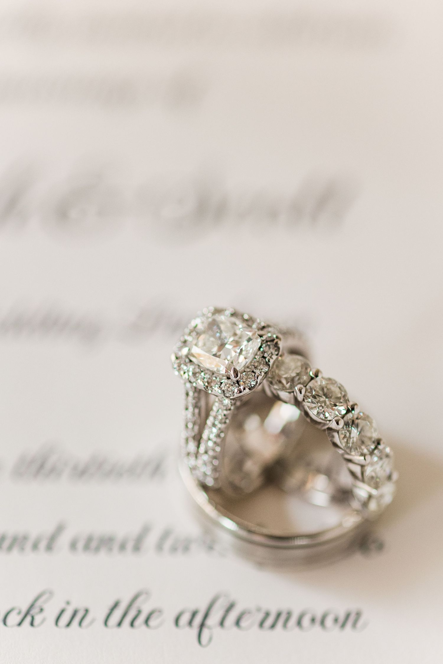 Elegant diamond engagement ring and wedding band set photographed on printed text.