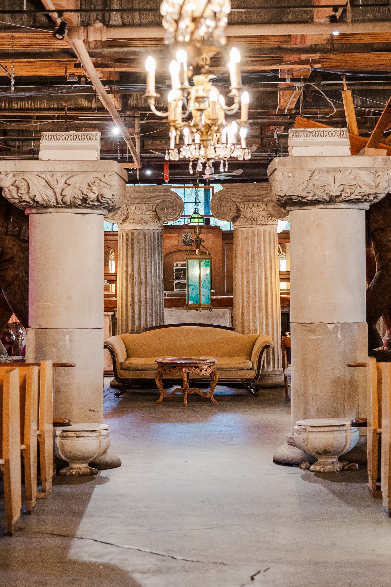 Grand interior space with classical columns, crystal chandeliers and vintage furniture in warm lighting.