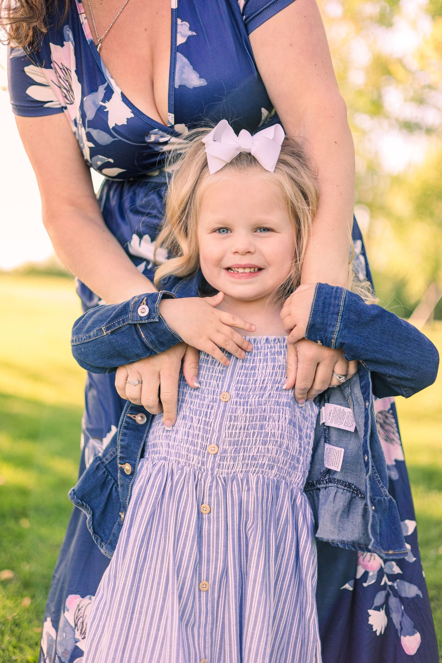 Blue floral dress and denim jacket fashion details shown in an outdoor spring portrait.