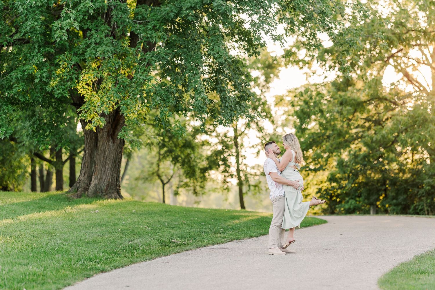 A person in a flowing dress walks gracefully along a curved park path in evening light.