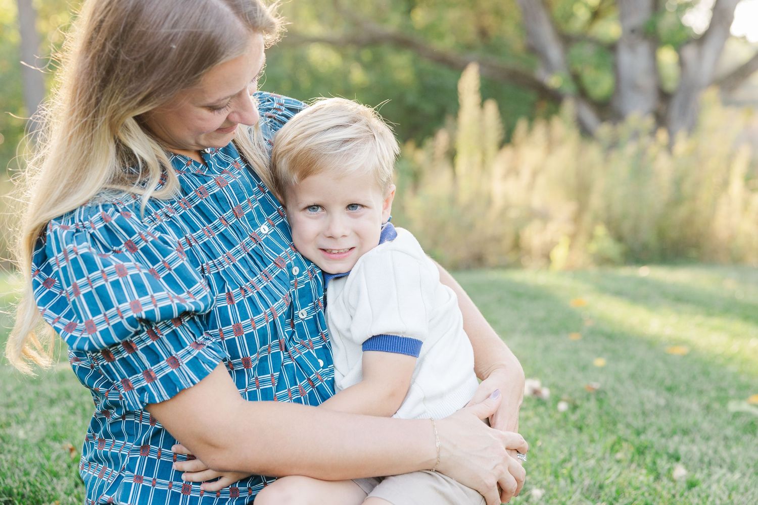 Candid outdoor family photography session in a grassy field during golden hour with natural lighting.
