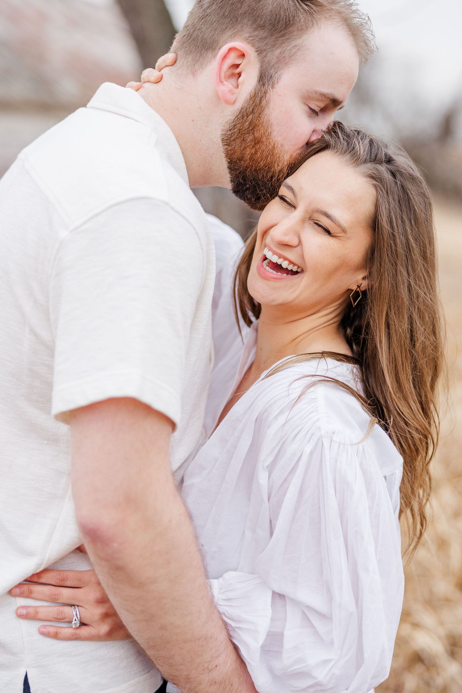Couple embracing during pregnancy announcement photos at Sands Main Street Prairie in Cary, Illinois