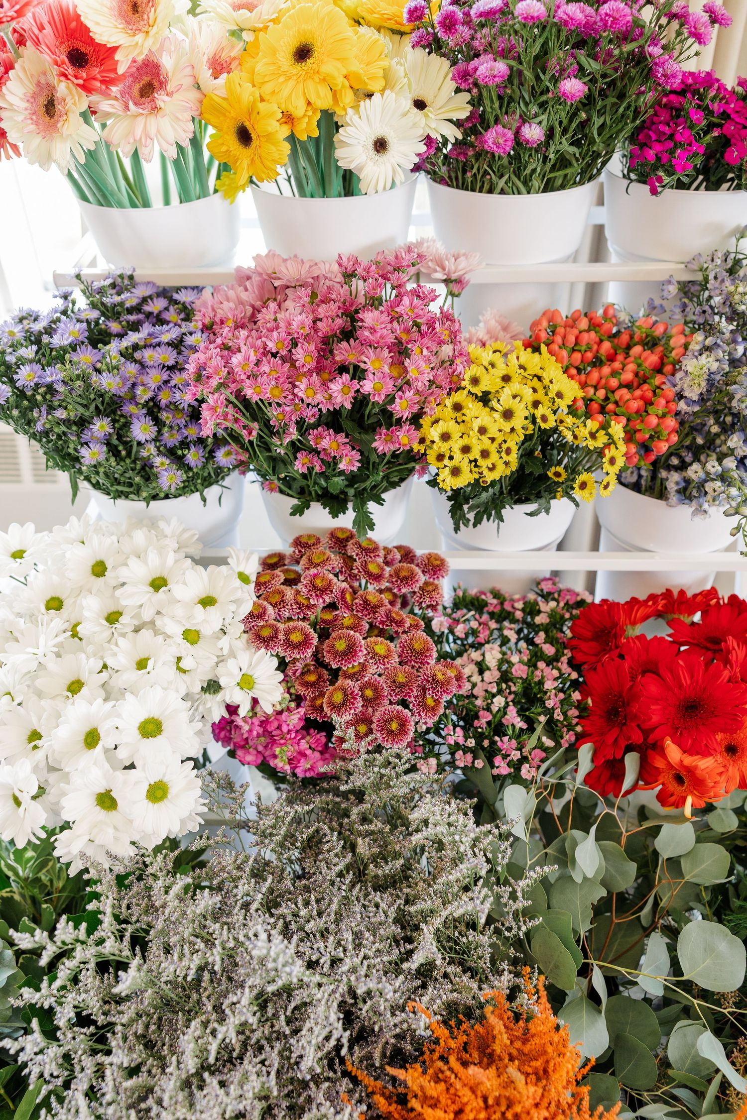 Colorful wildflower bouquets including daisies and roses on tiered stand
