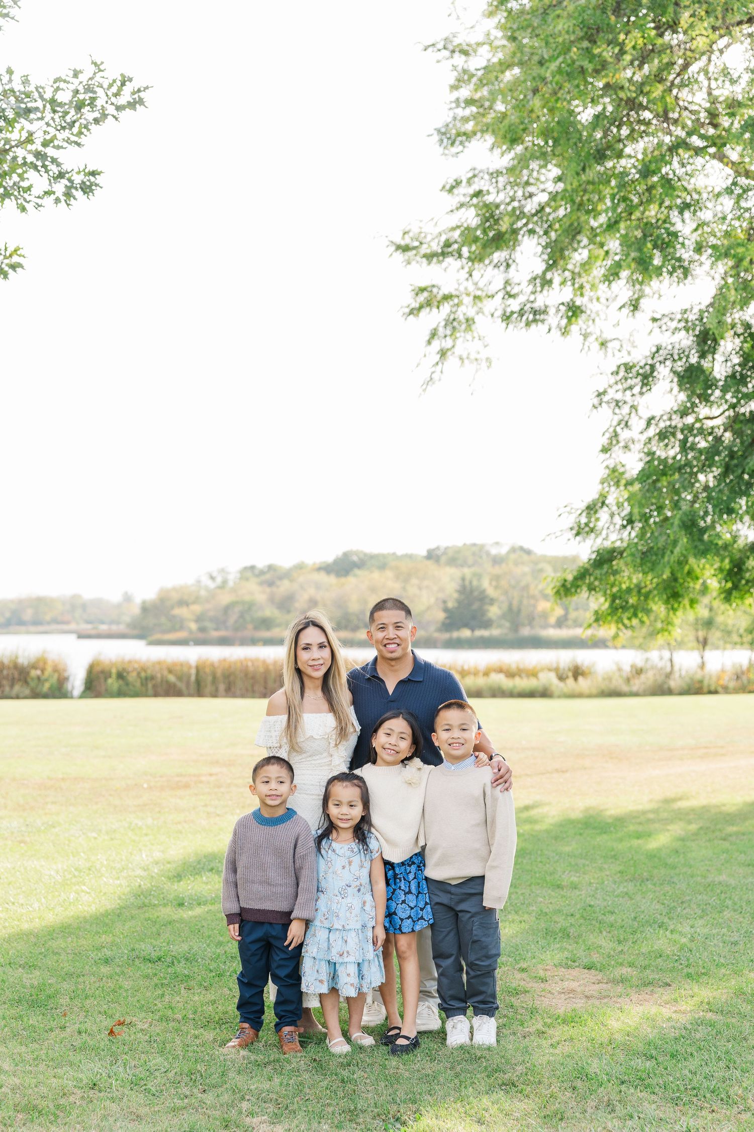A group stands together on a grassy hill during golden hour with trees and open fields in the background. Busse Woods