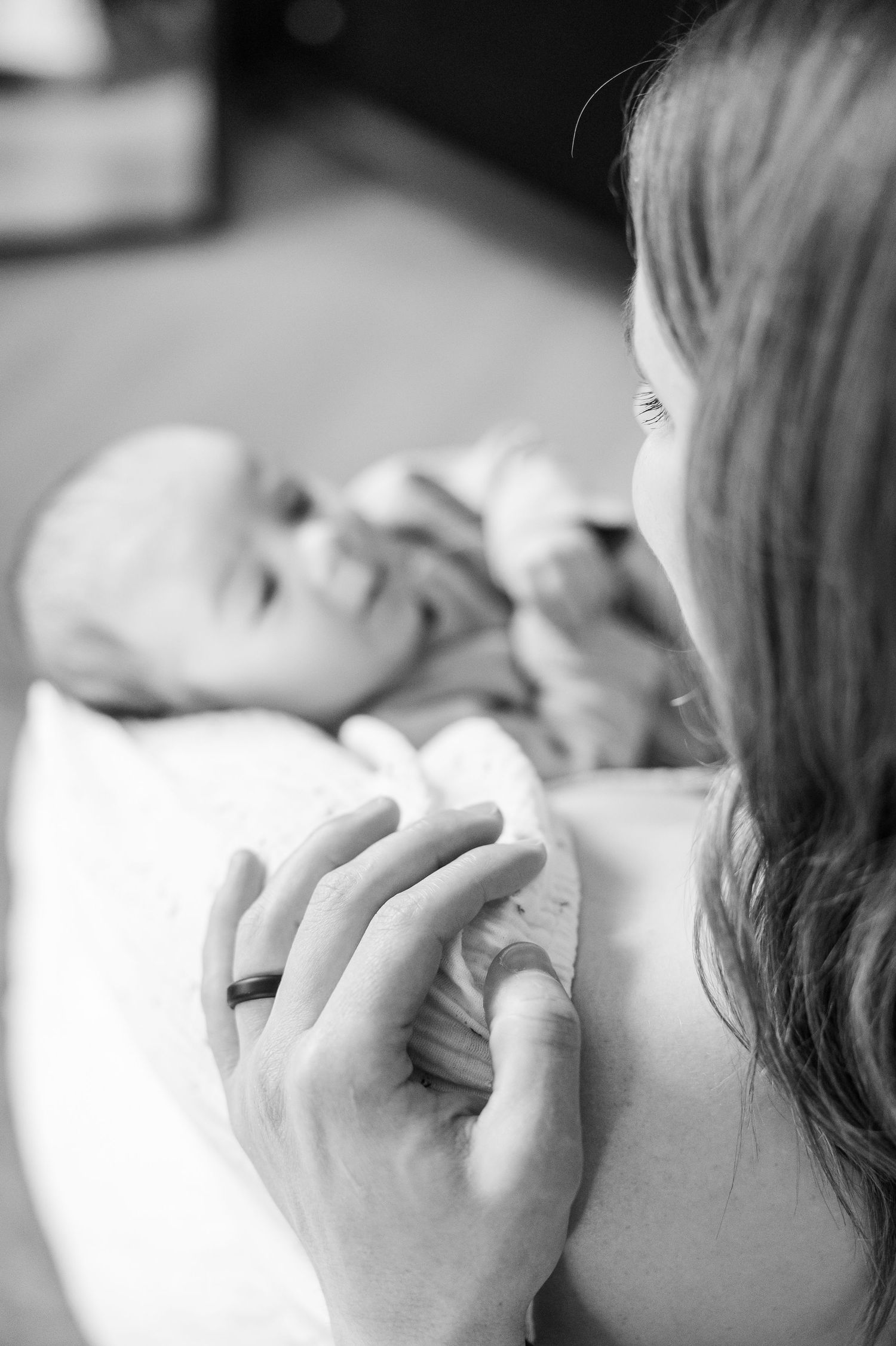 Black and white image of mother holding her newborn baby during an in-home lifestyle newborn session in Palatine IL