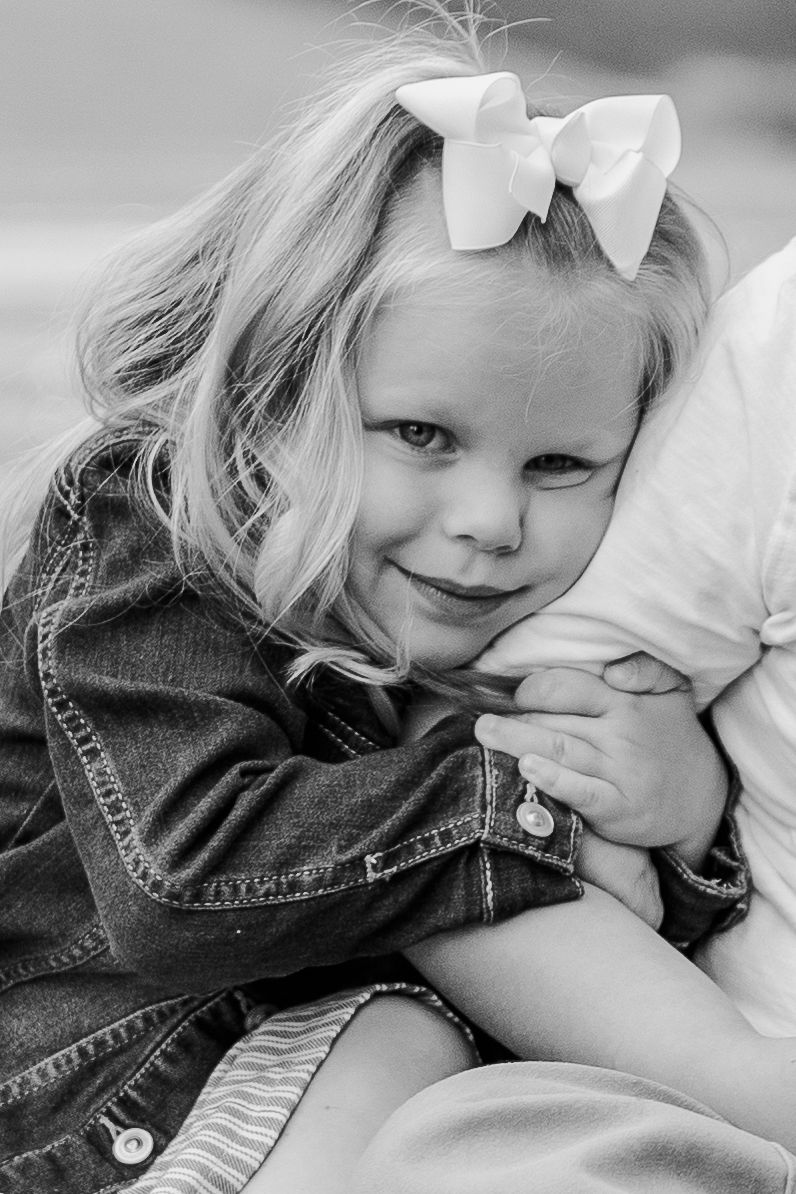 Close-up portrait in black and white showing a denim jacket and white bow.