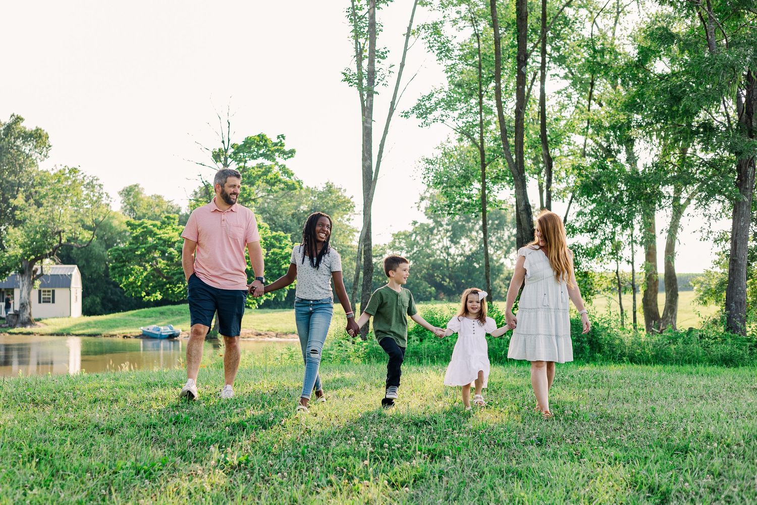 A family walks together holding hands through a scenic park on a sunny afternoon.
