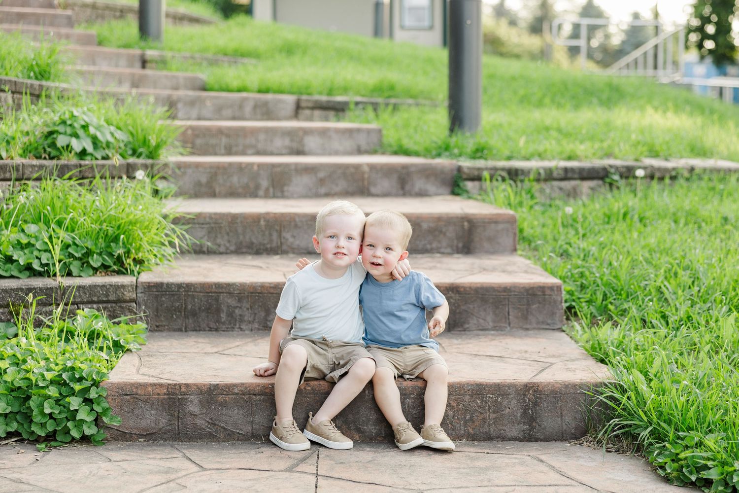 A series of candid images captured on outdoor stone steps surrounded by grass and greenery shows playful interactions.