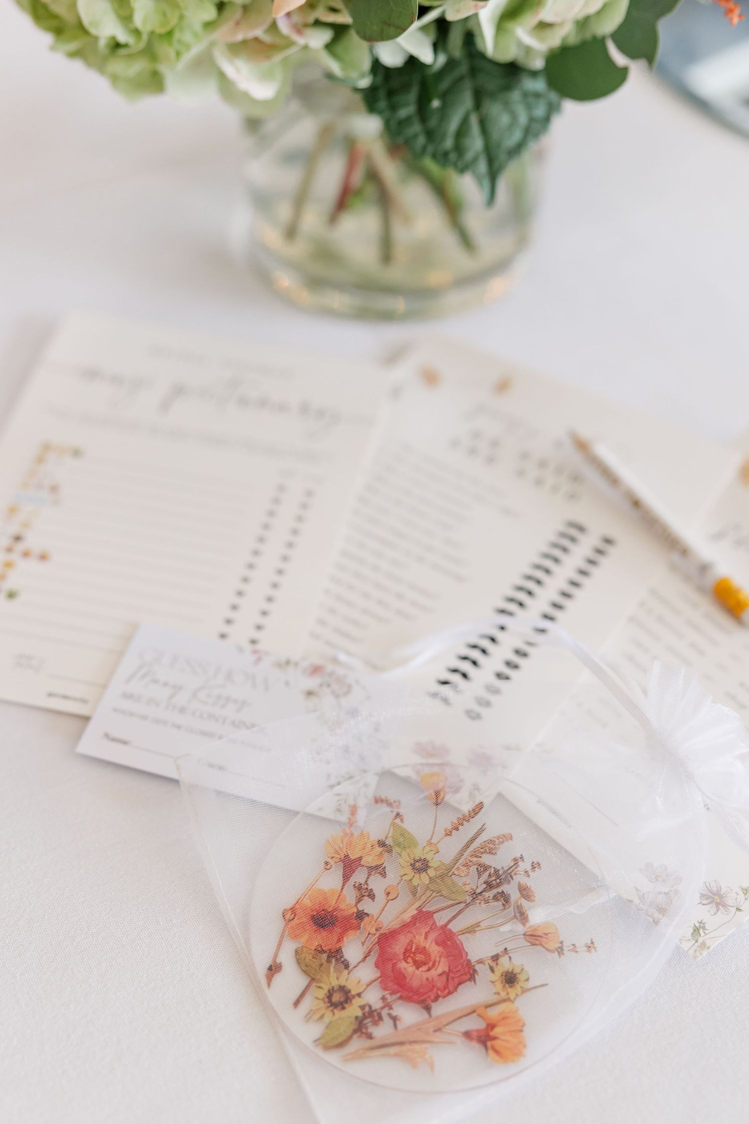 Wedding bridal shower stationery and floral favor bags arranged on a white table with hydrangeas.