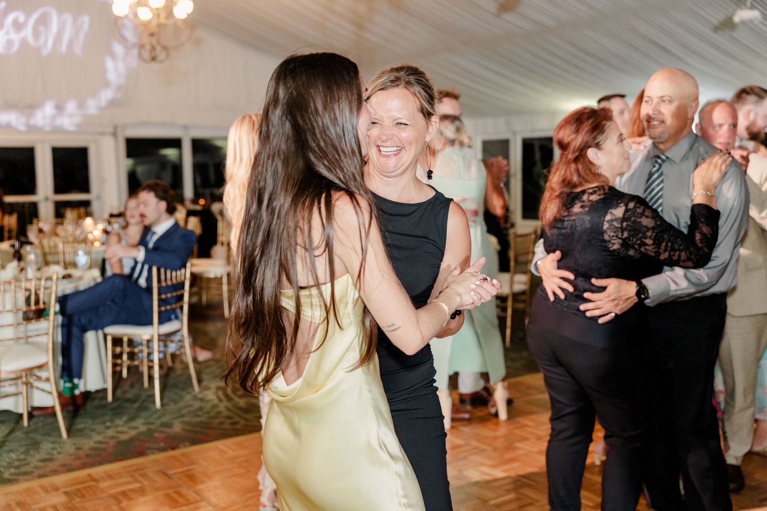 Guests dancing and smiling on the dance floor during lively wedding reception celebration.