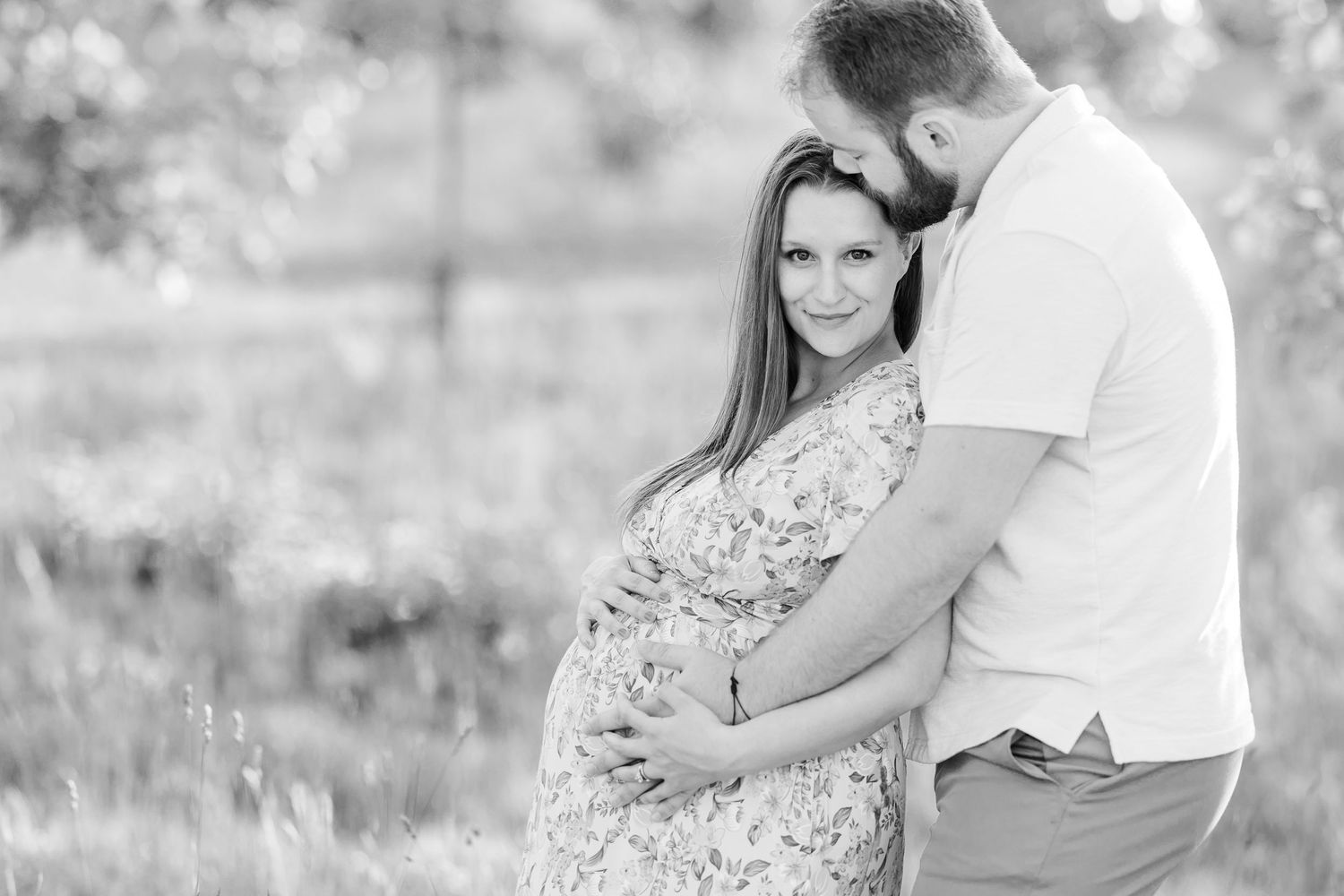Black and white maternity portrait of expecting parents cuddling together in the Cantigny gardens