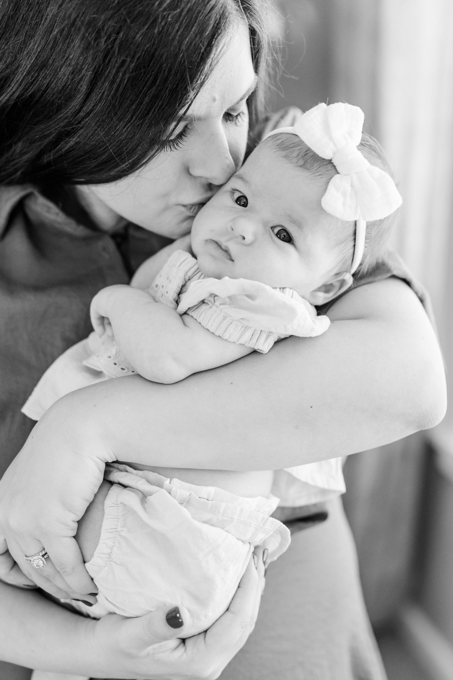 Black and white newborn photo of mom holding baby girl close during an in-home lifestyle session