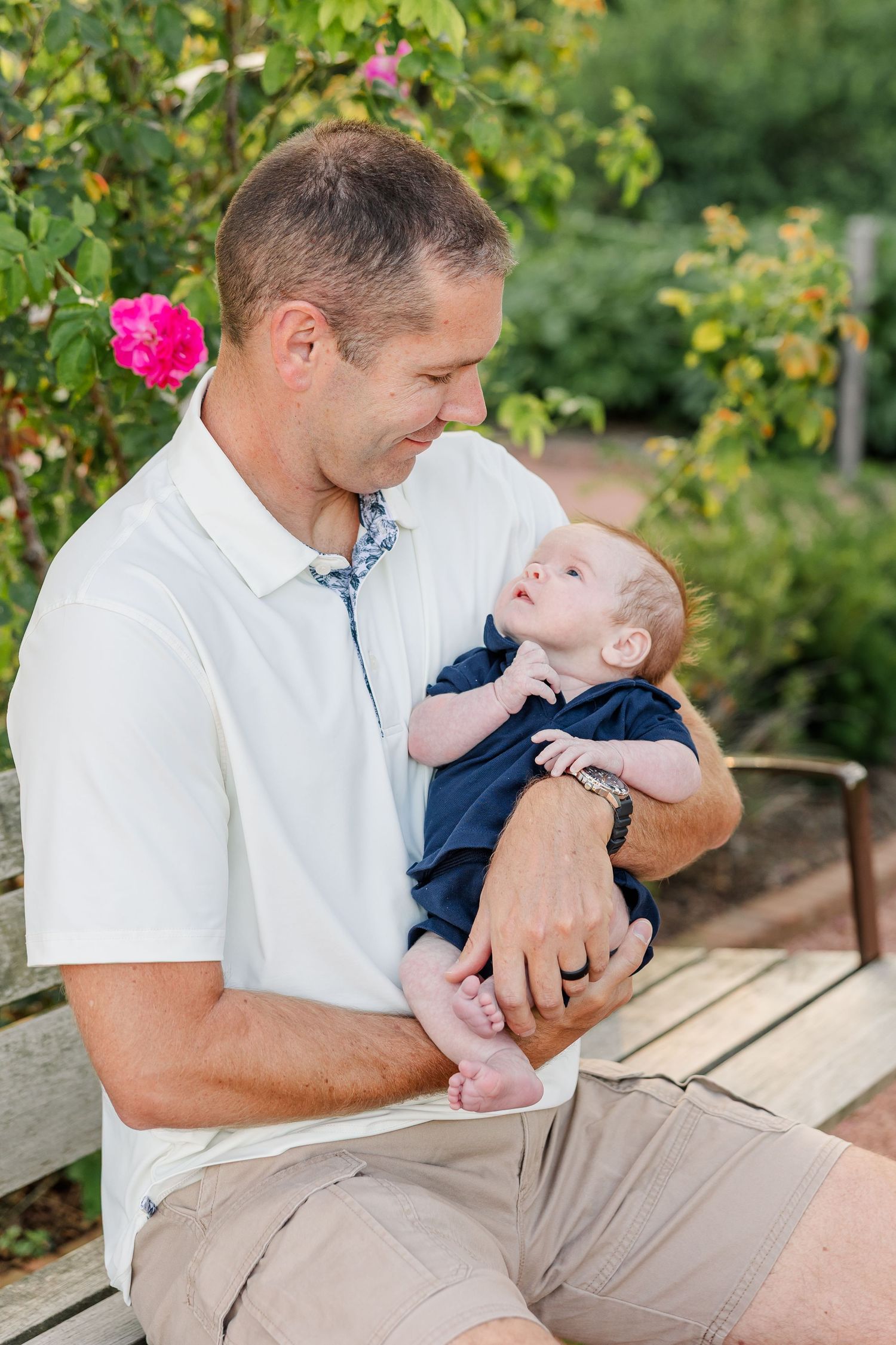 Andrew smiling down at baby Lincoln during their relaxed outdoor family session at Cantigny Park.