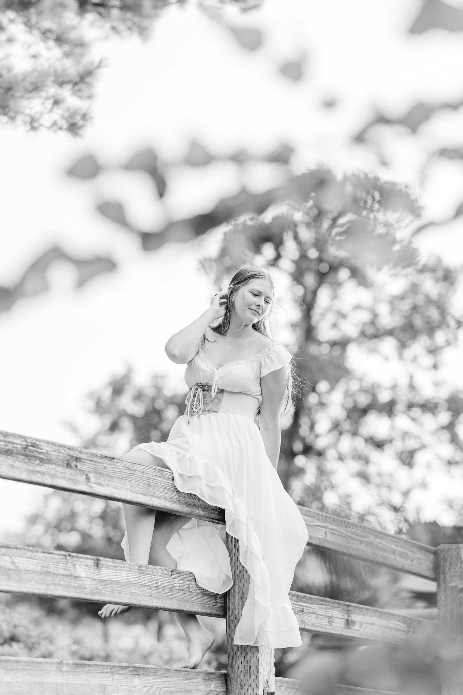 Black-and-white portrait of Samantha sitting on a rustic bridge during her Bartlett High School senior session.