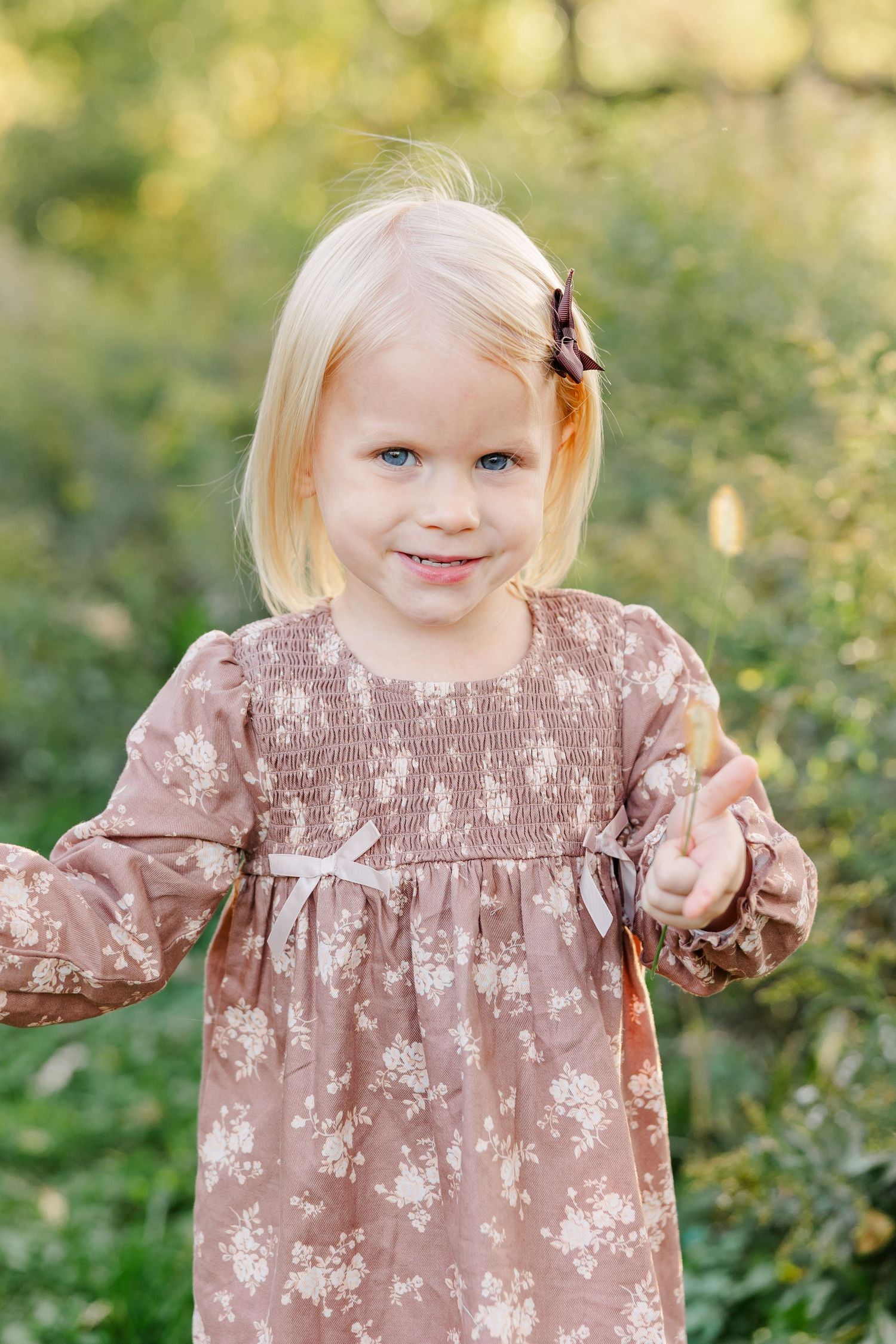 Young girl in a floral dress smiling during fall family photos in her St. Charles, IL backyard.