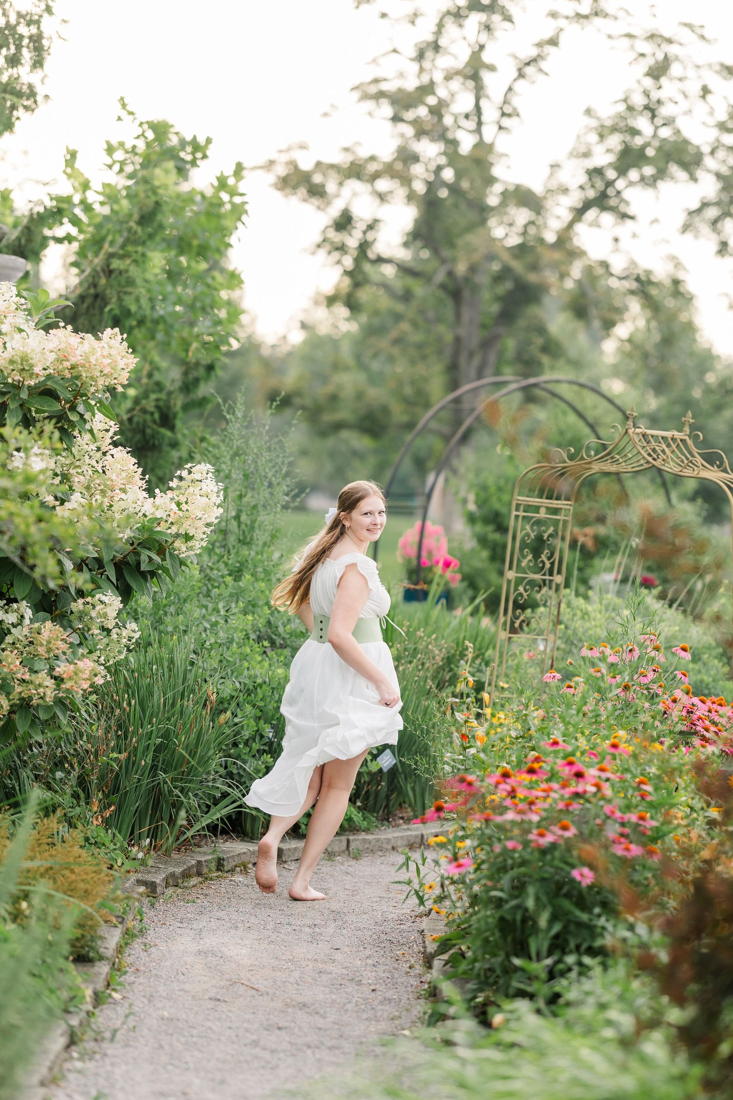 Joyful senior portrait of Samantha running through the colorful summer gardens at Cantigny Park.