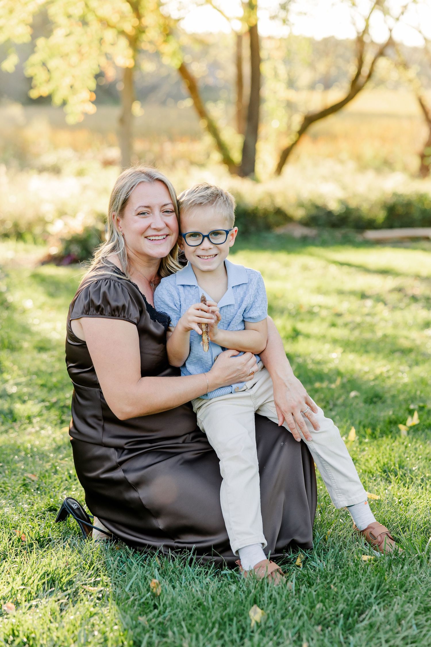Mom and son smiling together on the lawn during fall family portraits in St. Charles, IL.