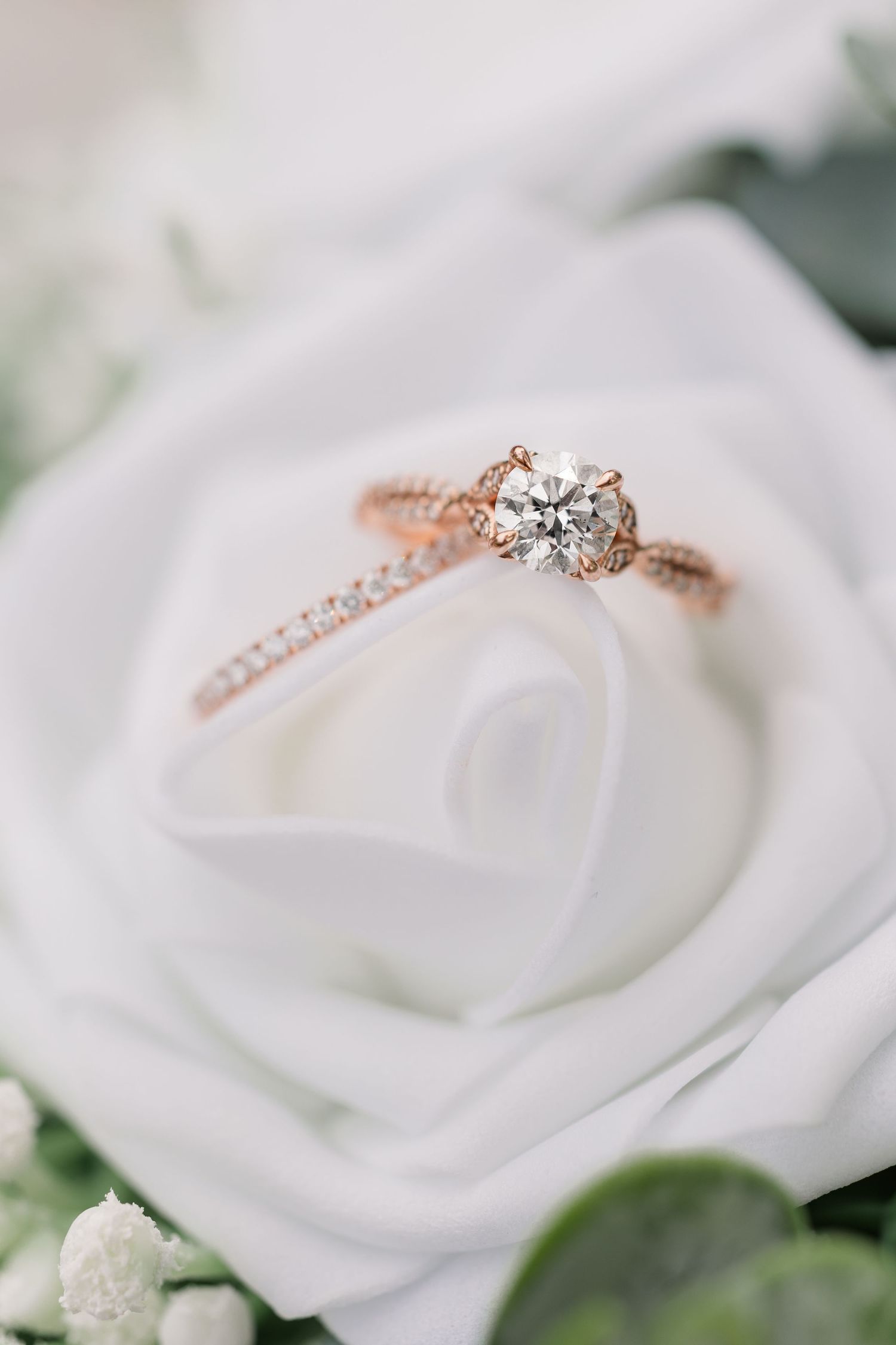 Close-up of Monika’s engagement ring and wedding band nestled inside a white rose.